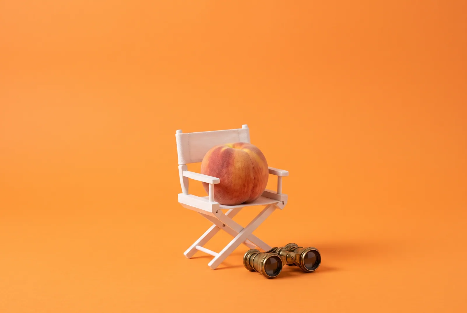 A peach in a tiny director's chair with opera glasses, the betrayed partner watching the evidence to rebuild trust after porn