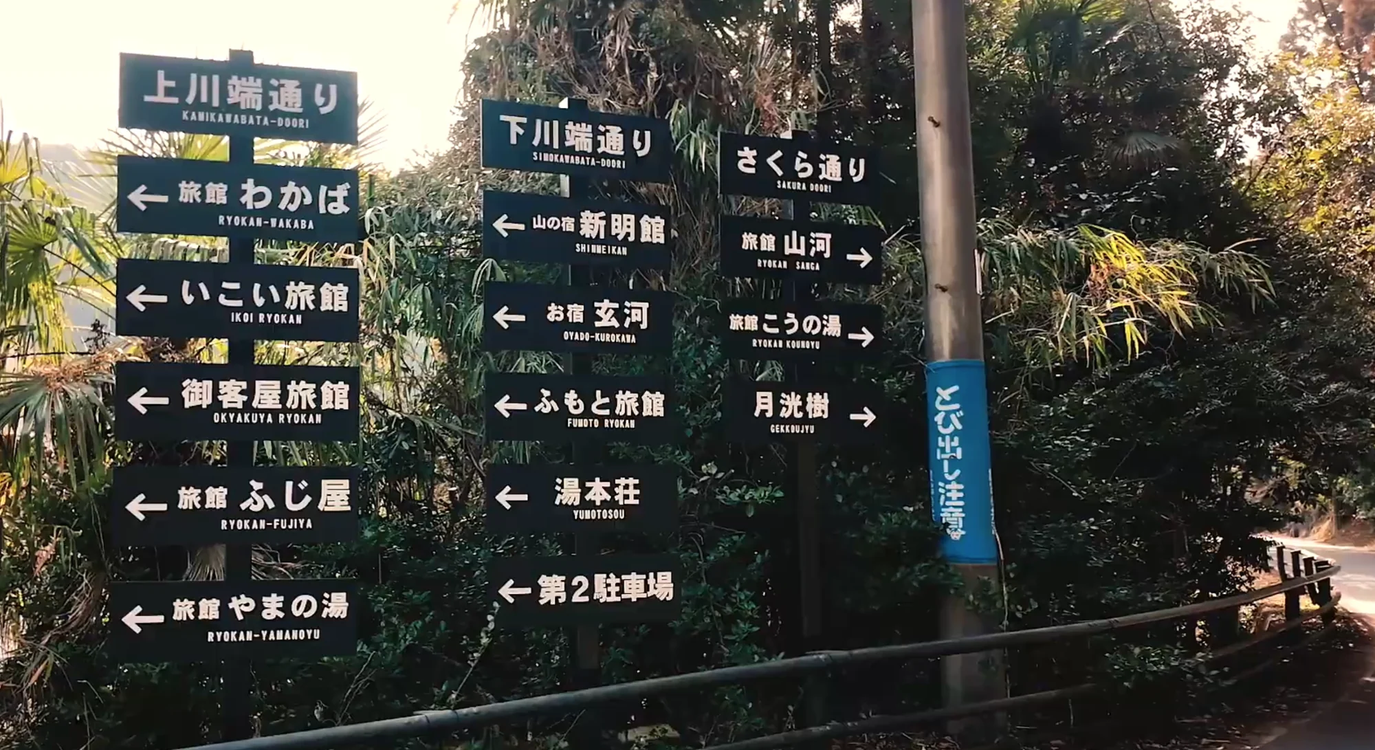 A village signpost listing Kurokawa's lanes and arrows to named ryokan