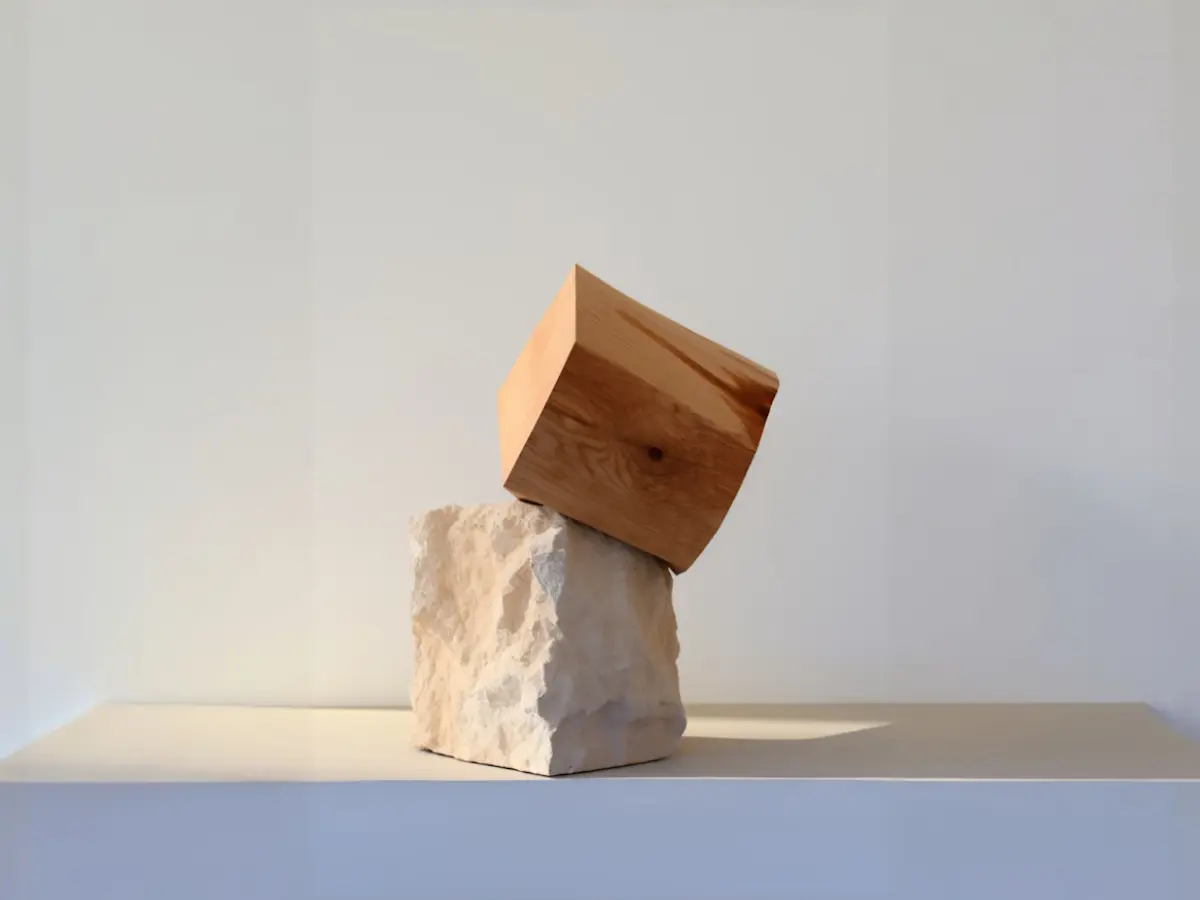 A cozy workspace featuring a wooden desk, a lamp, books, and a plant, illuminated by warm sunlight.