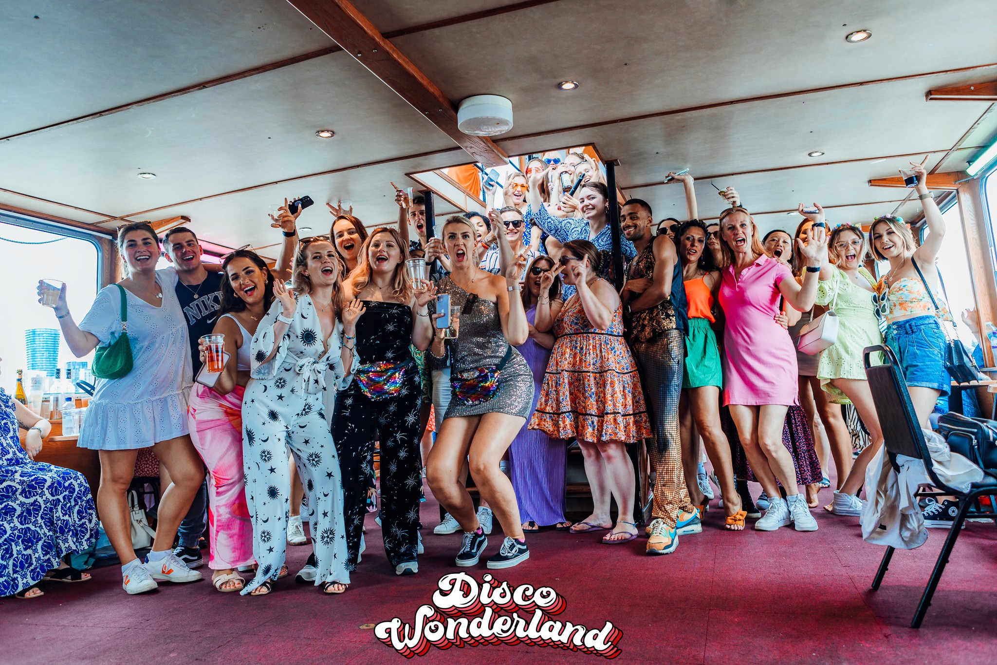 A packed, colourful interior deck of the ABBA boat party in London with guests dancing to disco anthems