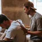 Een man legt zijn handen op de rug van een andere man