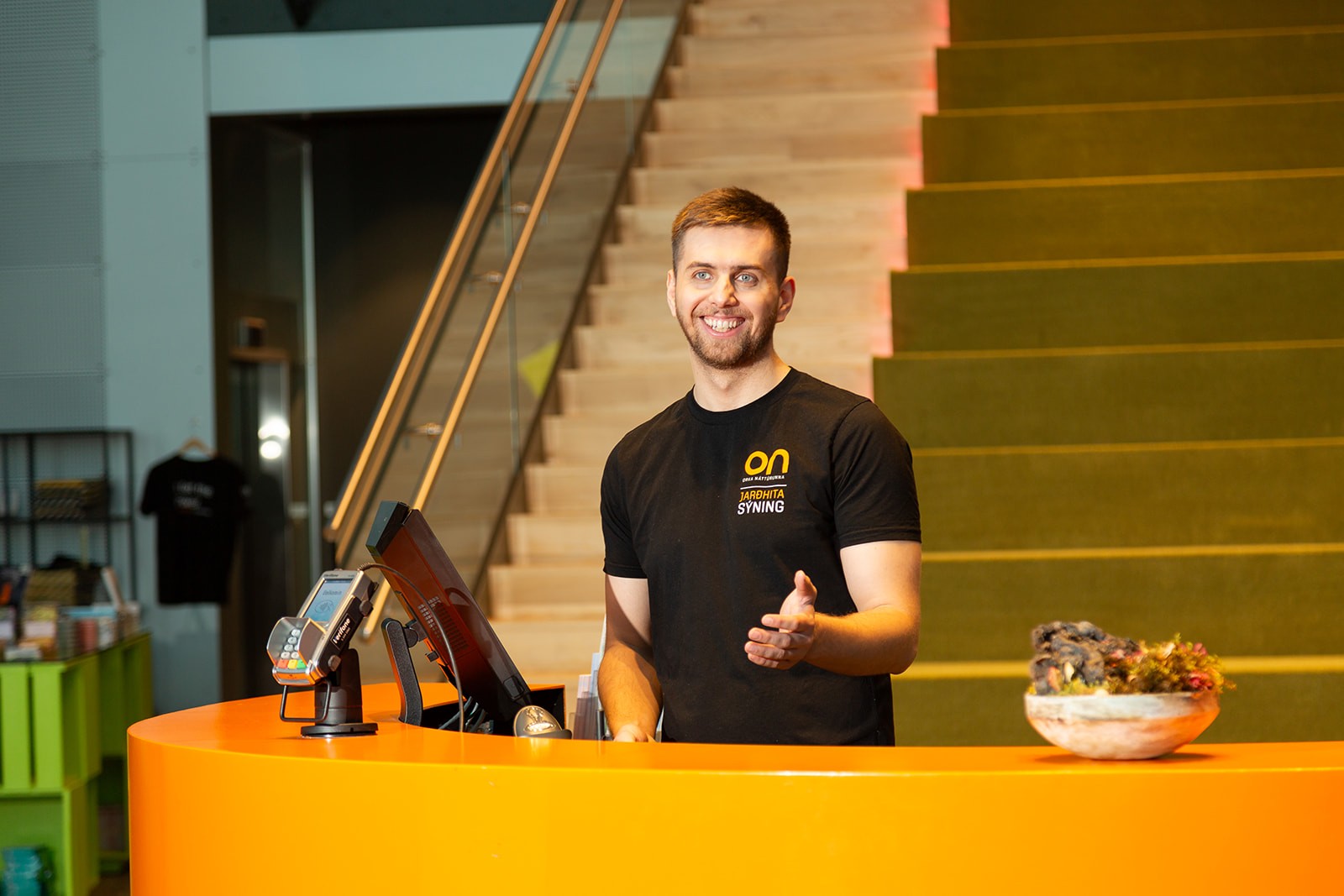 Visitors observing a circular glass installation inside a viewing area with large windows
