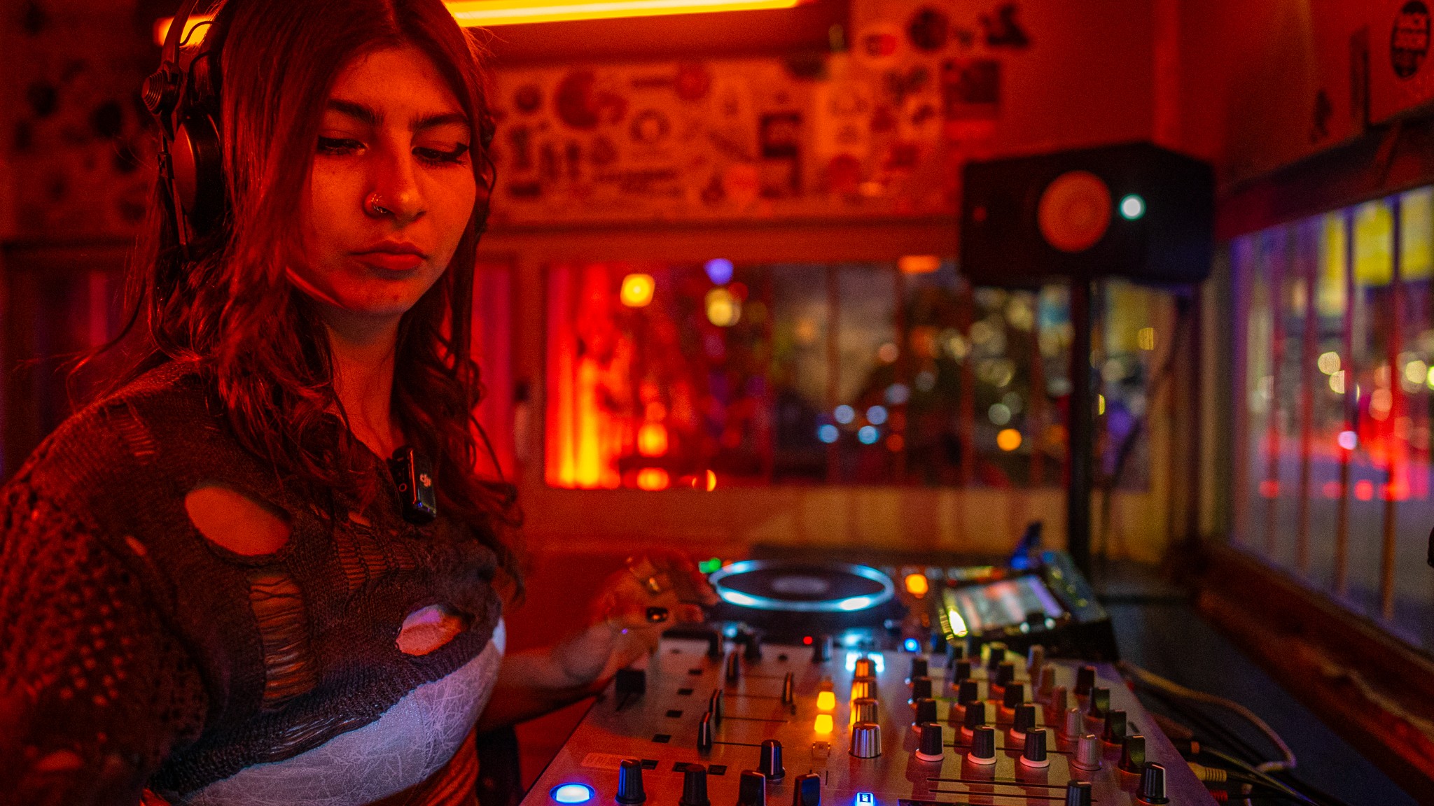 DJ mezclando en una cabina con iluminación roja