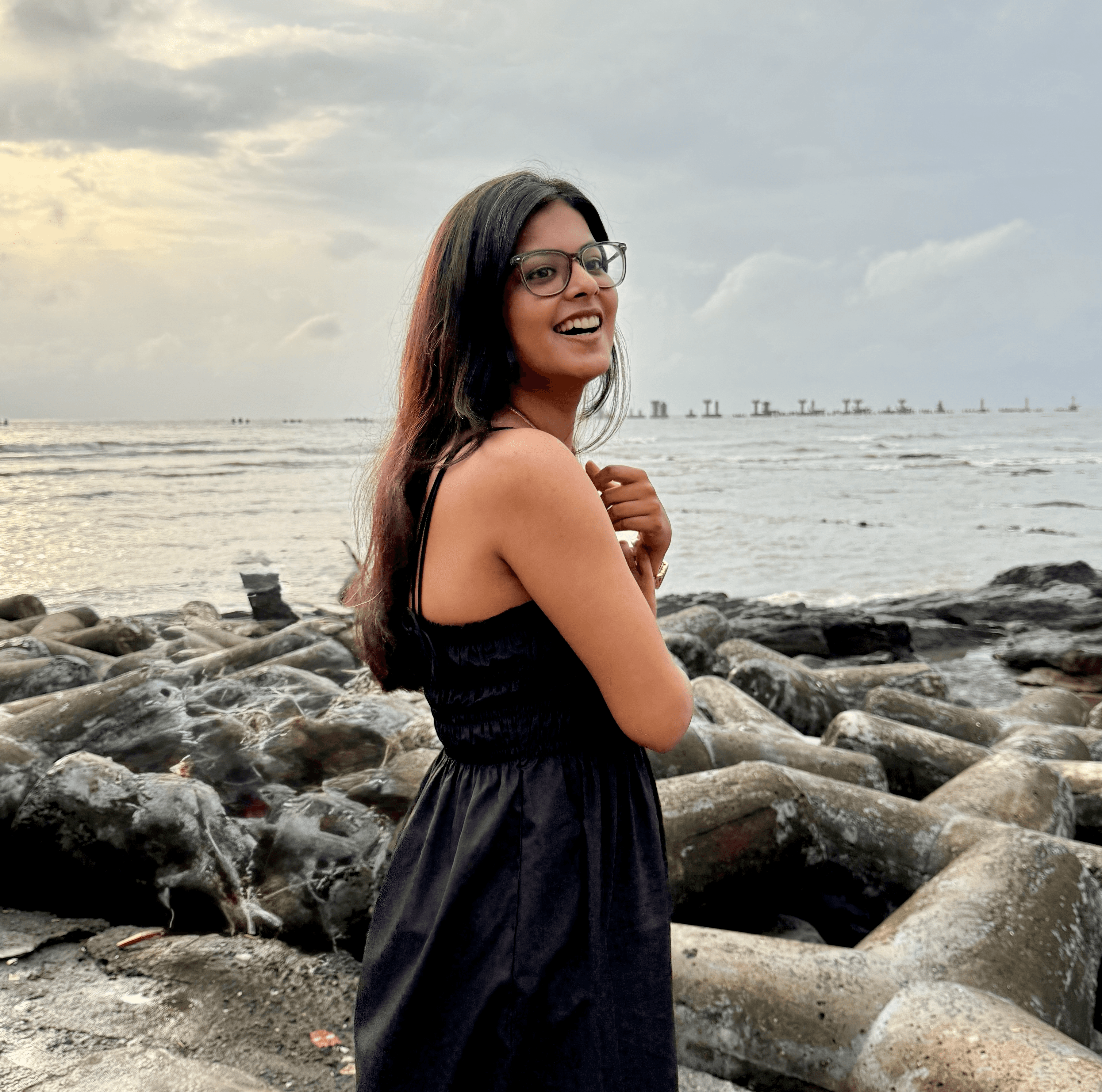 Person wearing a blue puffer jacket and red backpack standing in front of a light blue building on a city street.