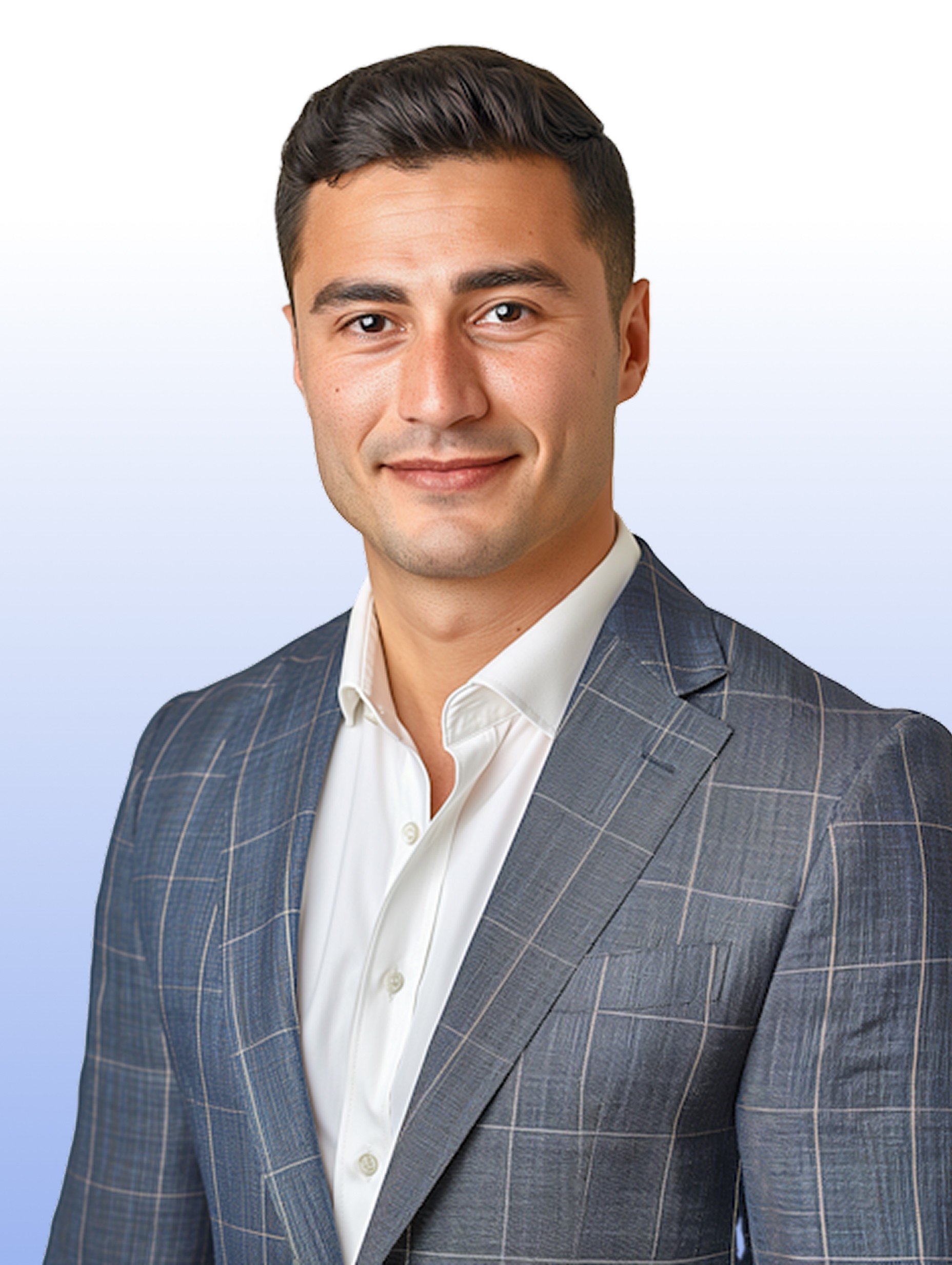 A man with blonde hair and a gray suit smiles warmly against a neutral background.