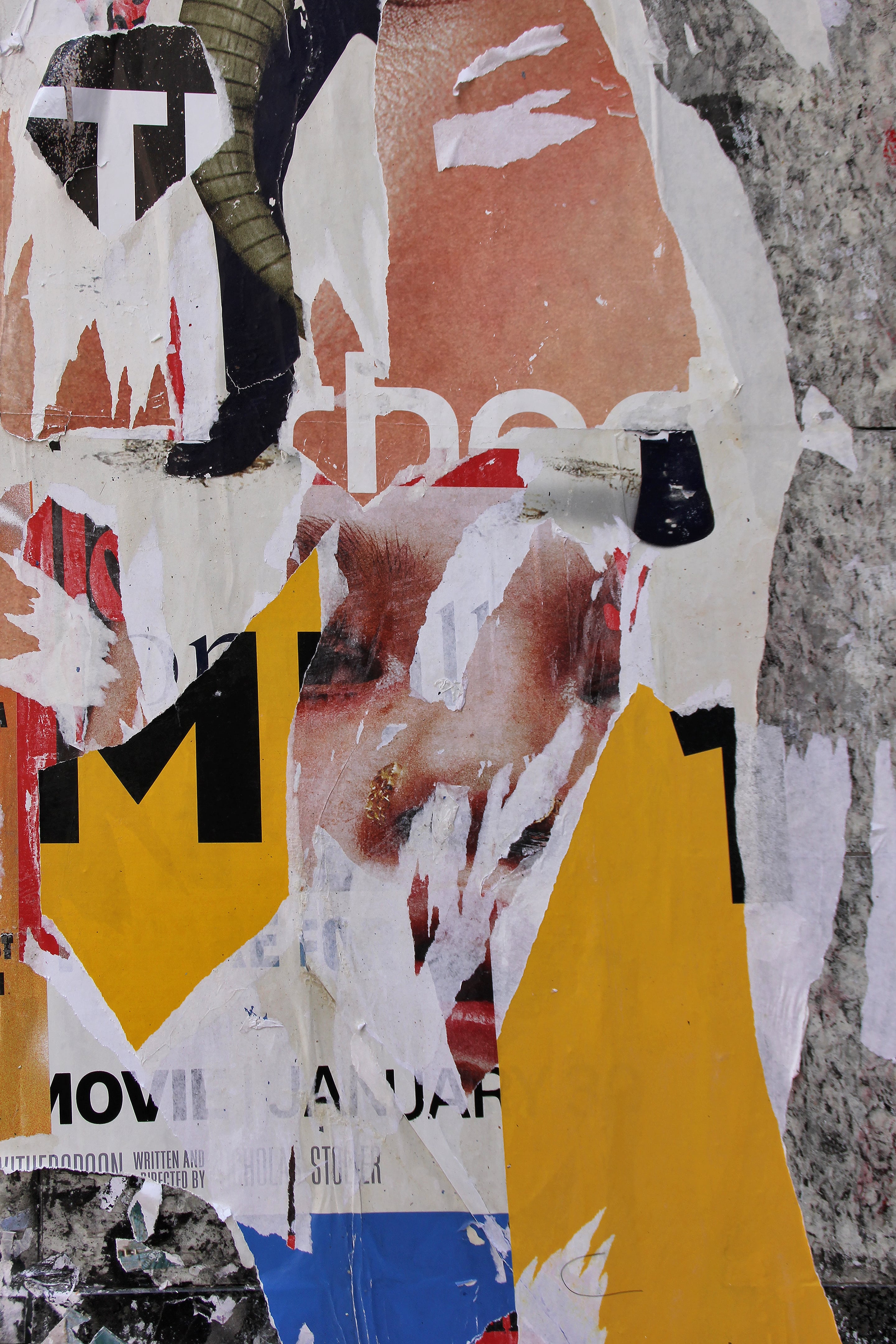 Close-up photograph of layered torn posters revealing partial text, a fragmented human face, and bold yellow shapes. The overlapping materials and exposed textures create an abstract study of time, advertising, and urban transformation.