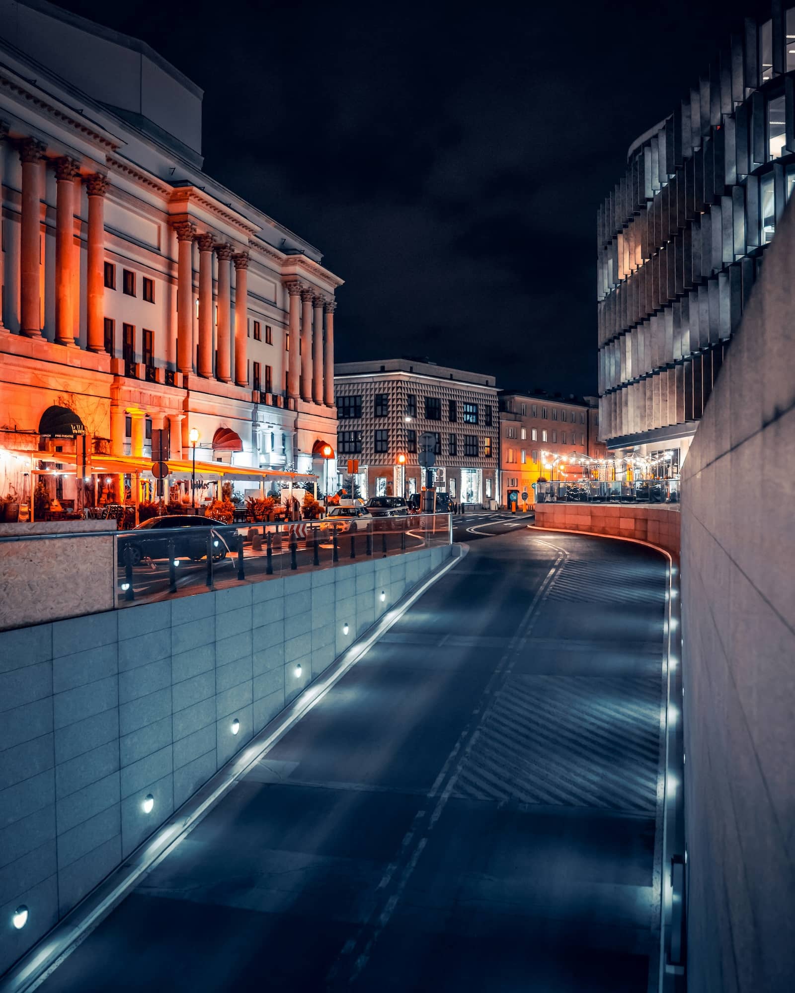 road in the city illuminated by road lights and a nearby building illuminated by orange light