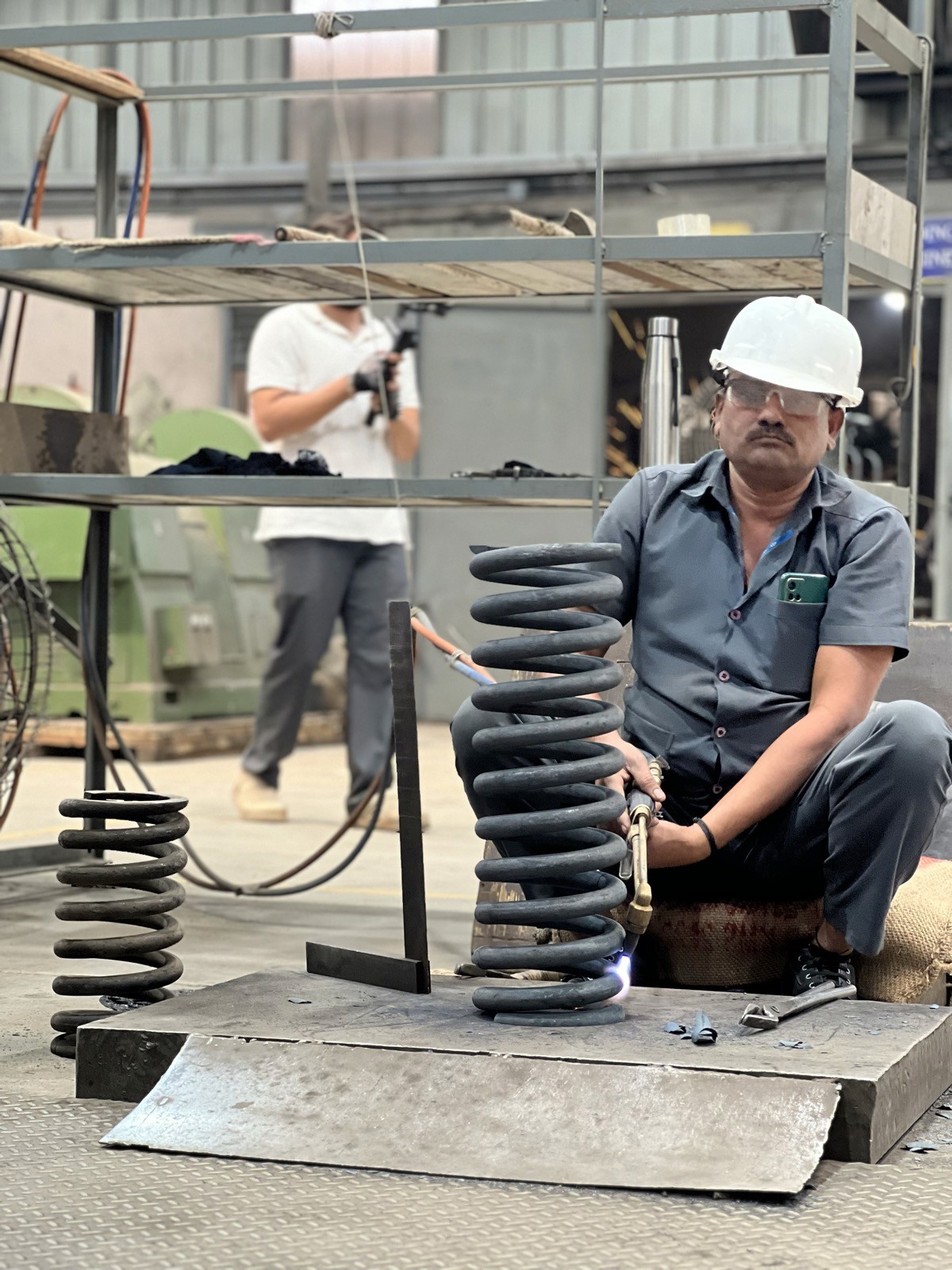 Indian factory storekeeper sorting spare parts by priority, representing VED inventory classification