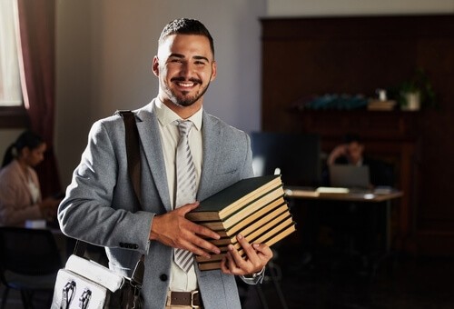 Man in suit and tie holding books