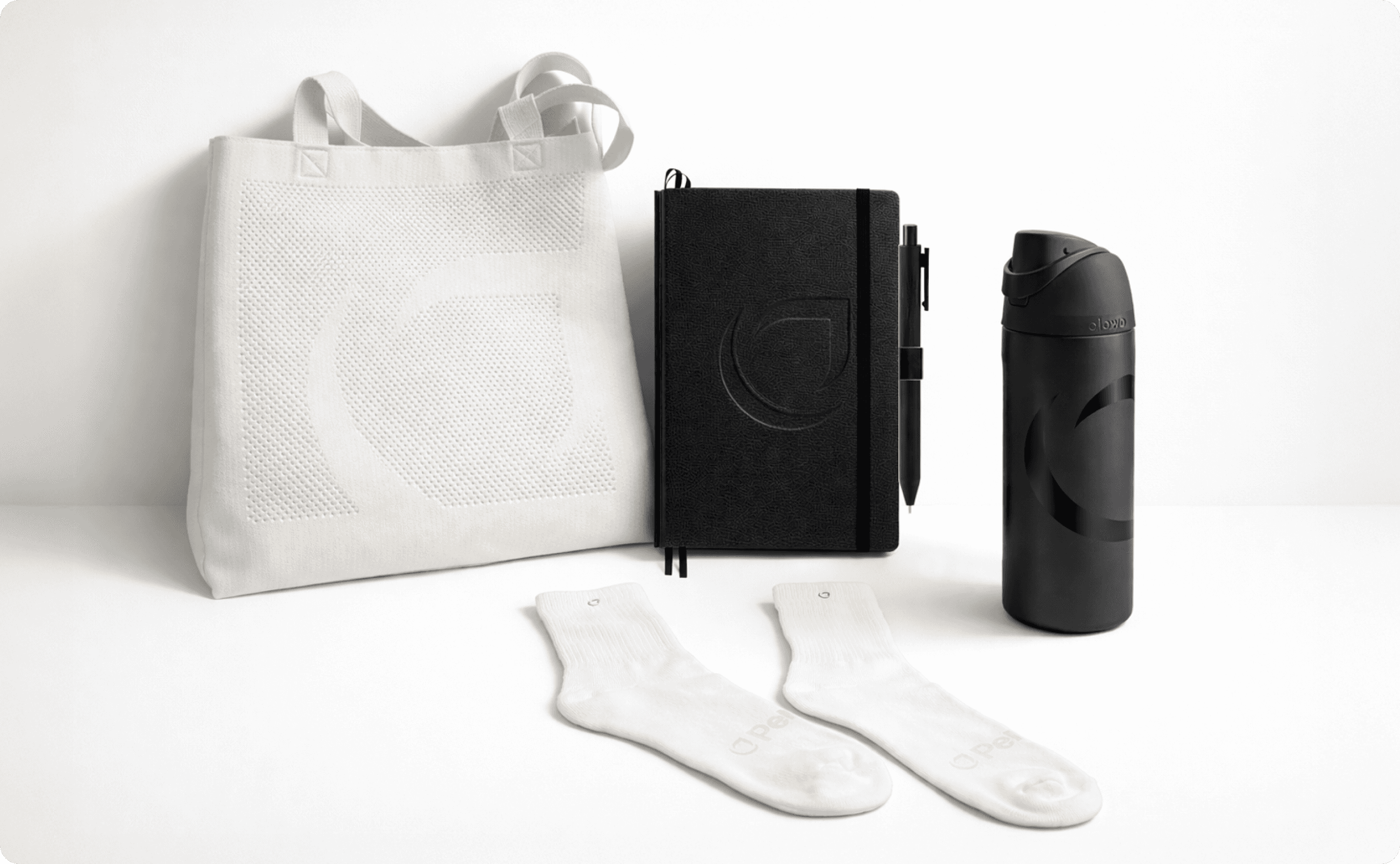 A white tote bag, notebook, tumbler, and a pair of white socks with the PerkUp logo.