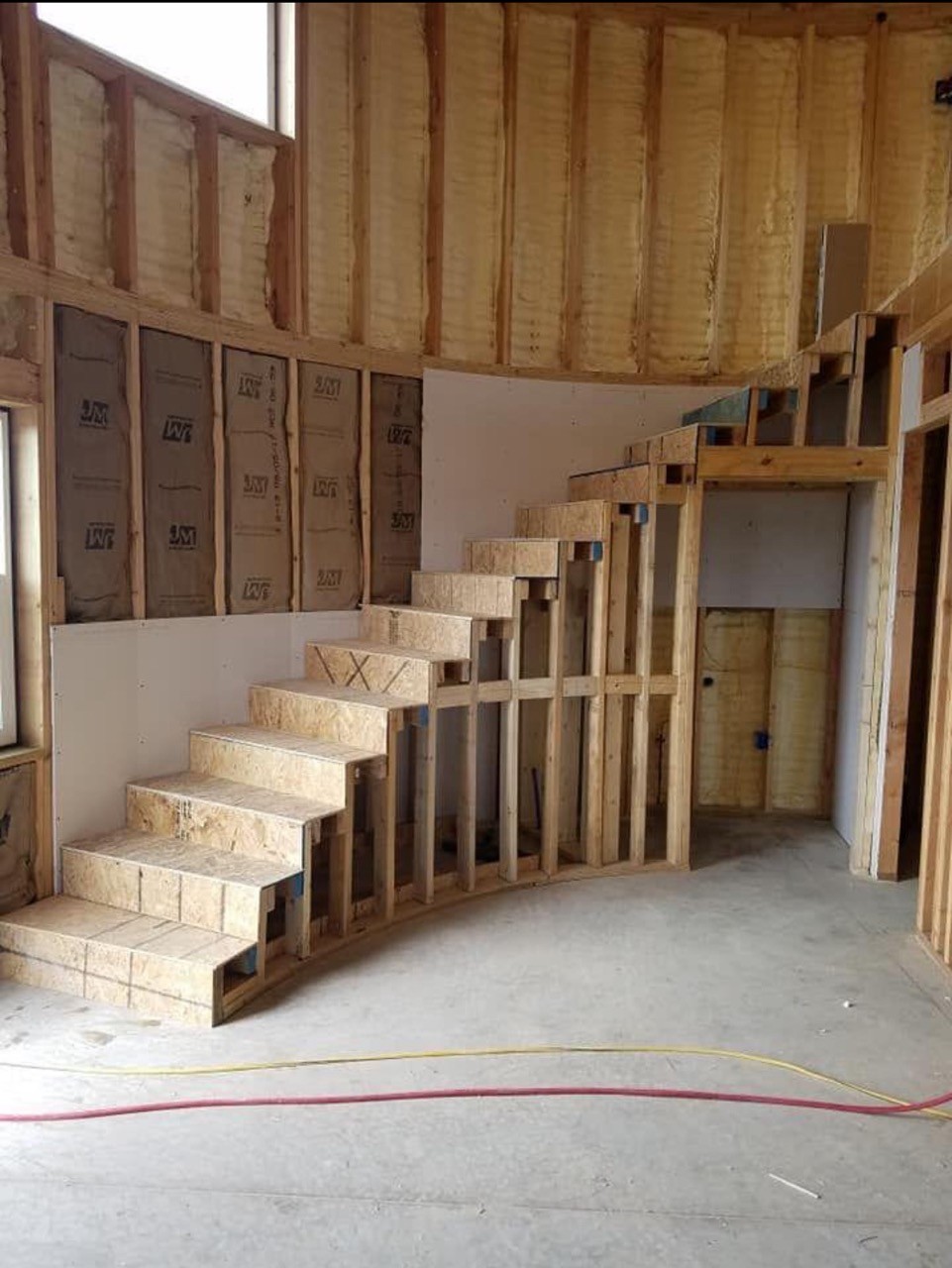Modern indoor space with large glass doors, lush greenery, and a cozy seating area visible beyond.