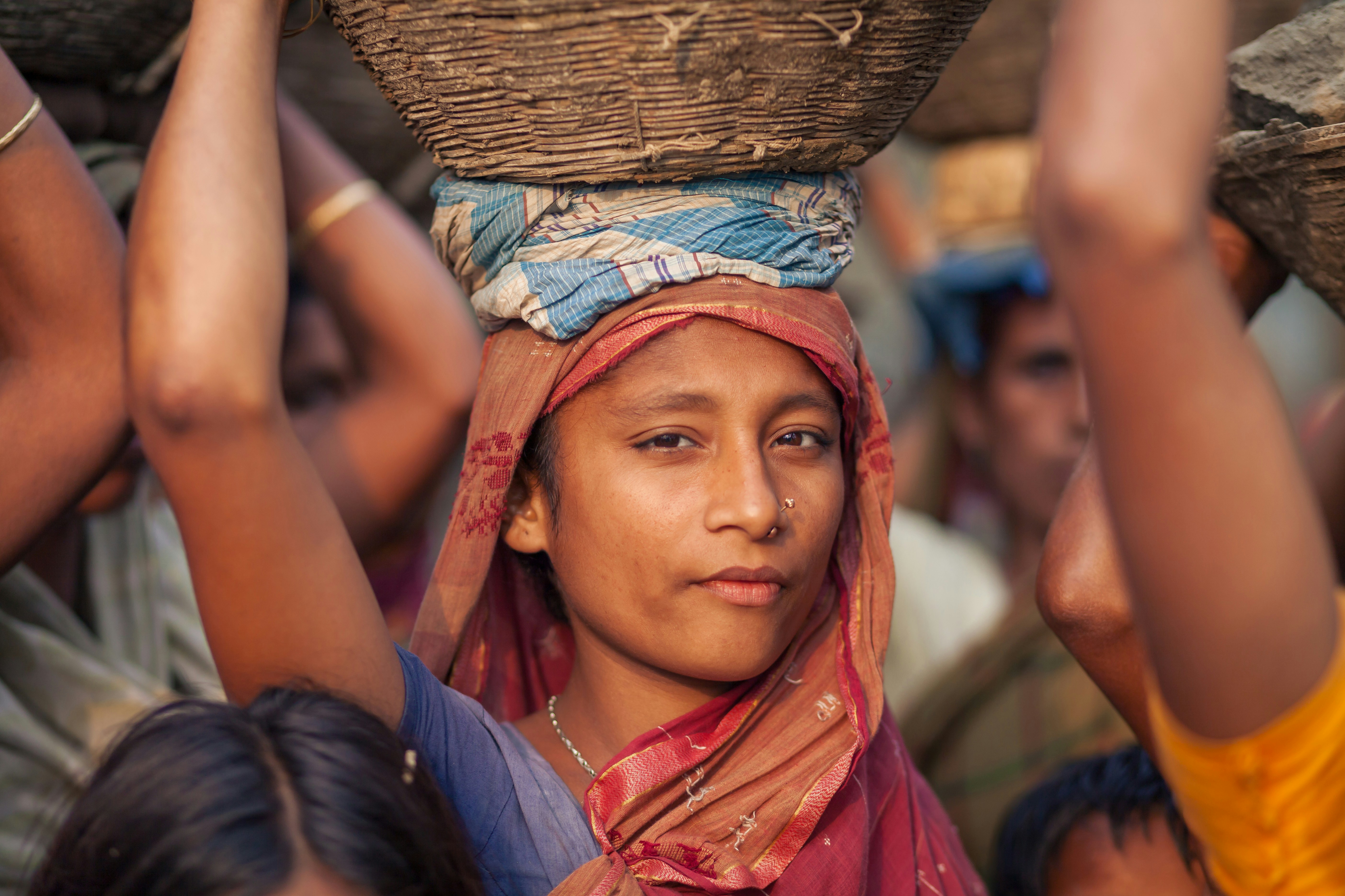 Woman carrying basket on her head with others