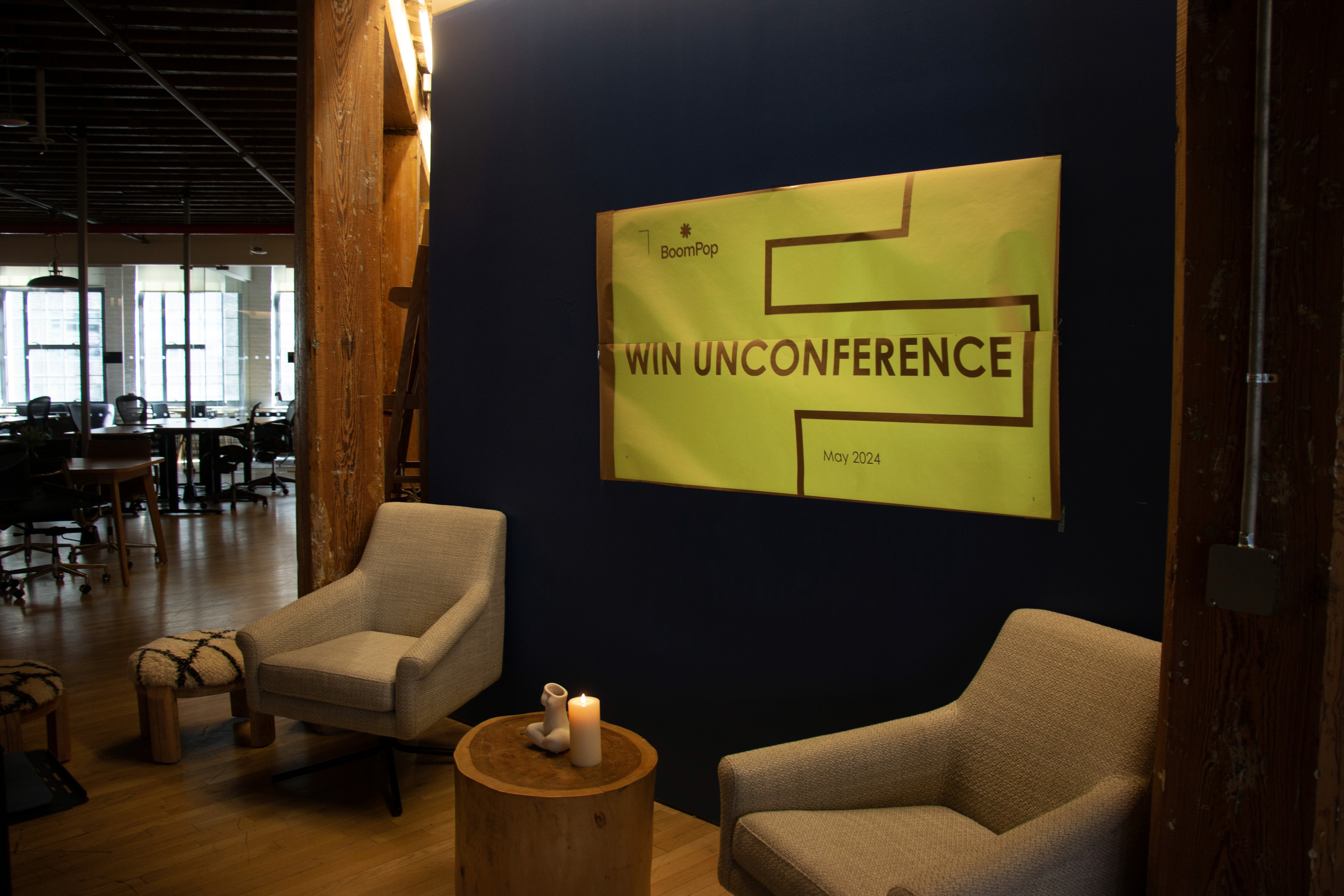 A cozy seating area featuring two light armchairs in front of a dark blue wall with a bright green artwork.