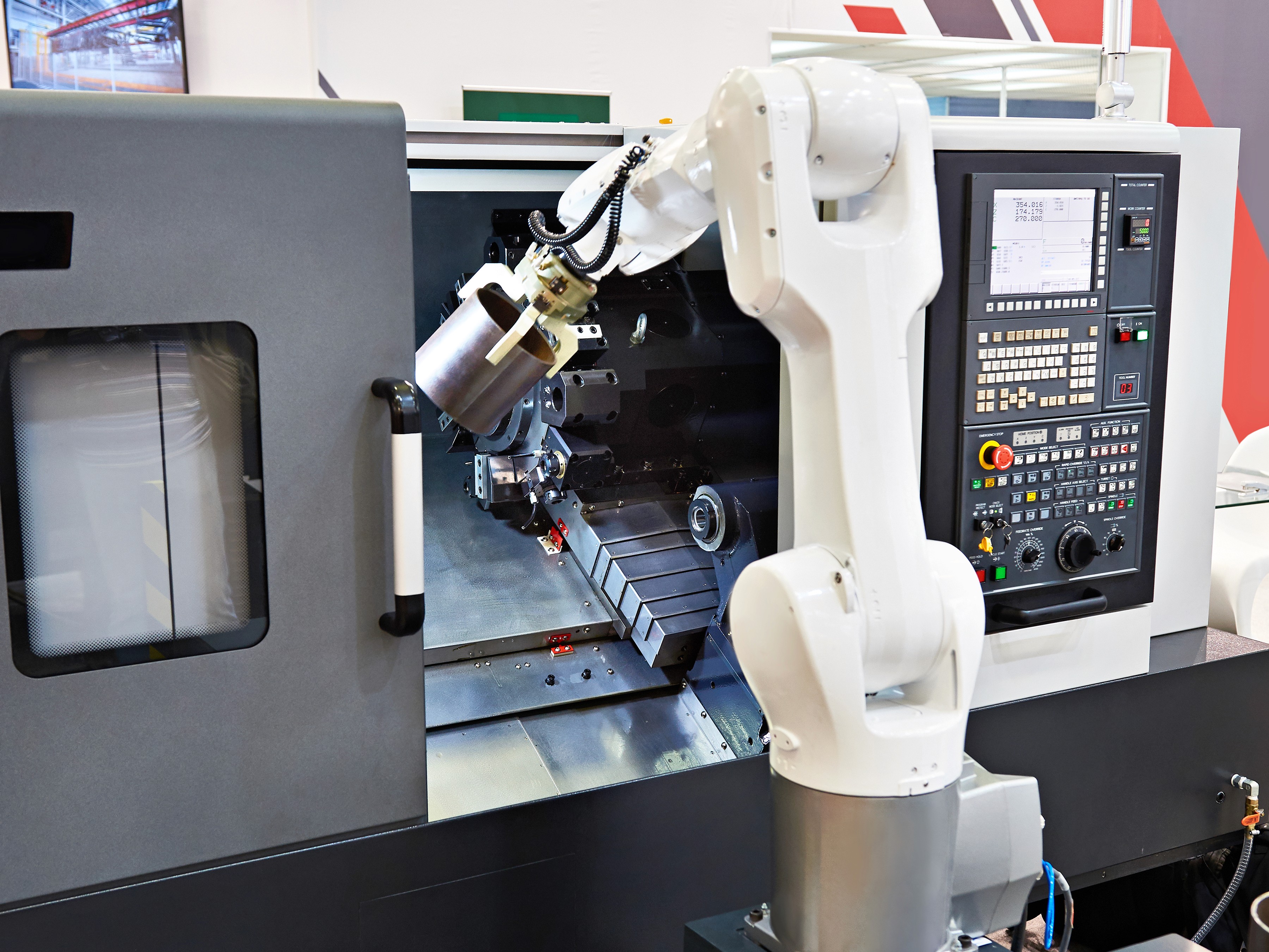 A robotic arm positioned near a machine, suggesting an automated manufacturing or assembly process.