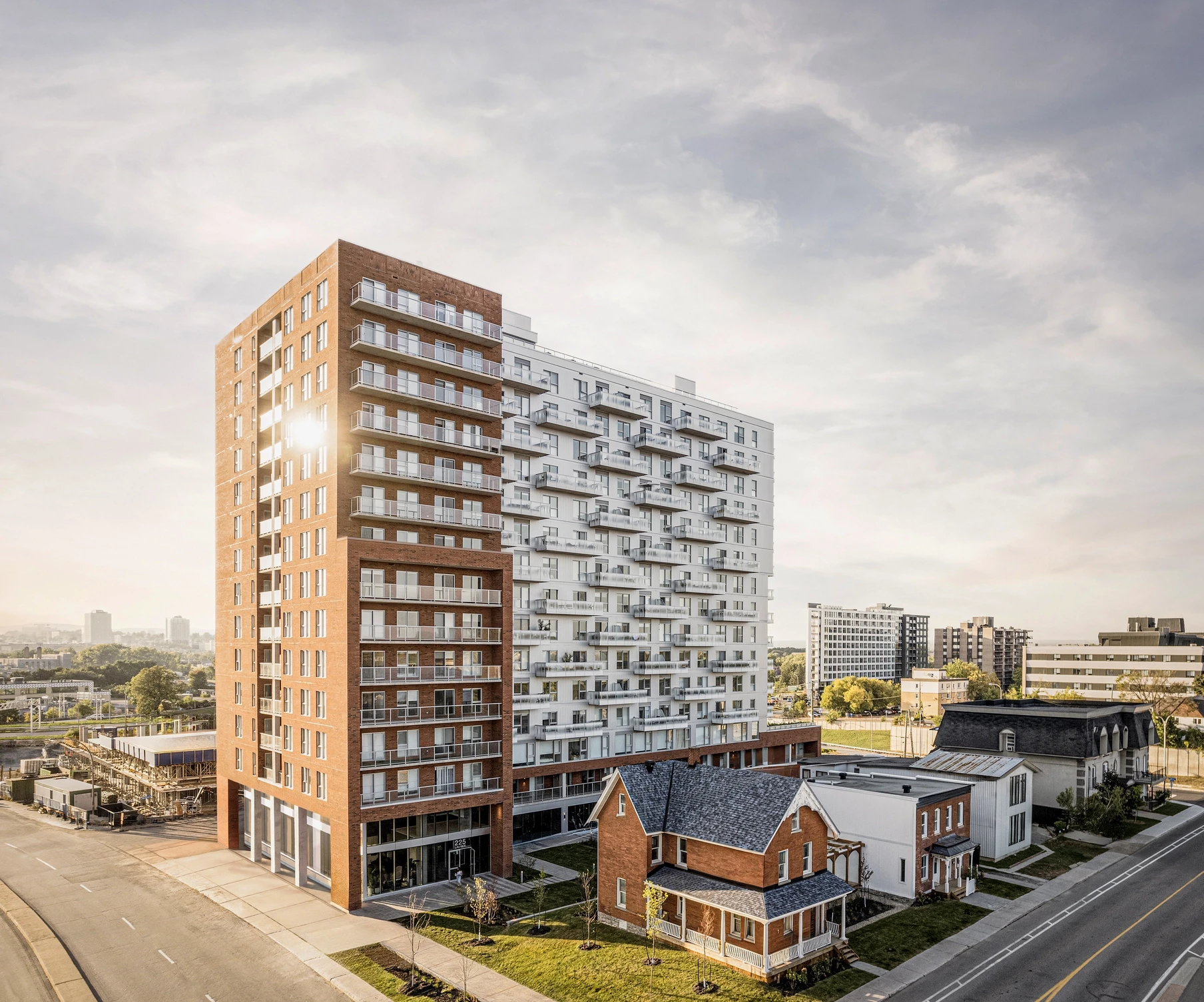 Ground-level perspective of Éléonore residential project, showing the relationship between the structural colonnade, glazed lobby, and surrounding streetscape.