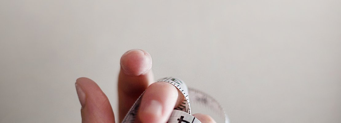 A tape measure tangled in between fingers