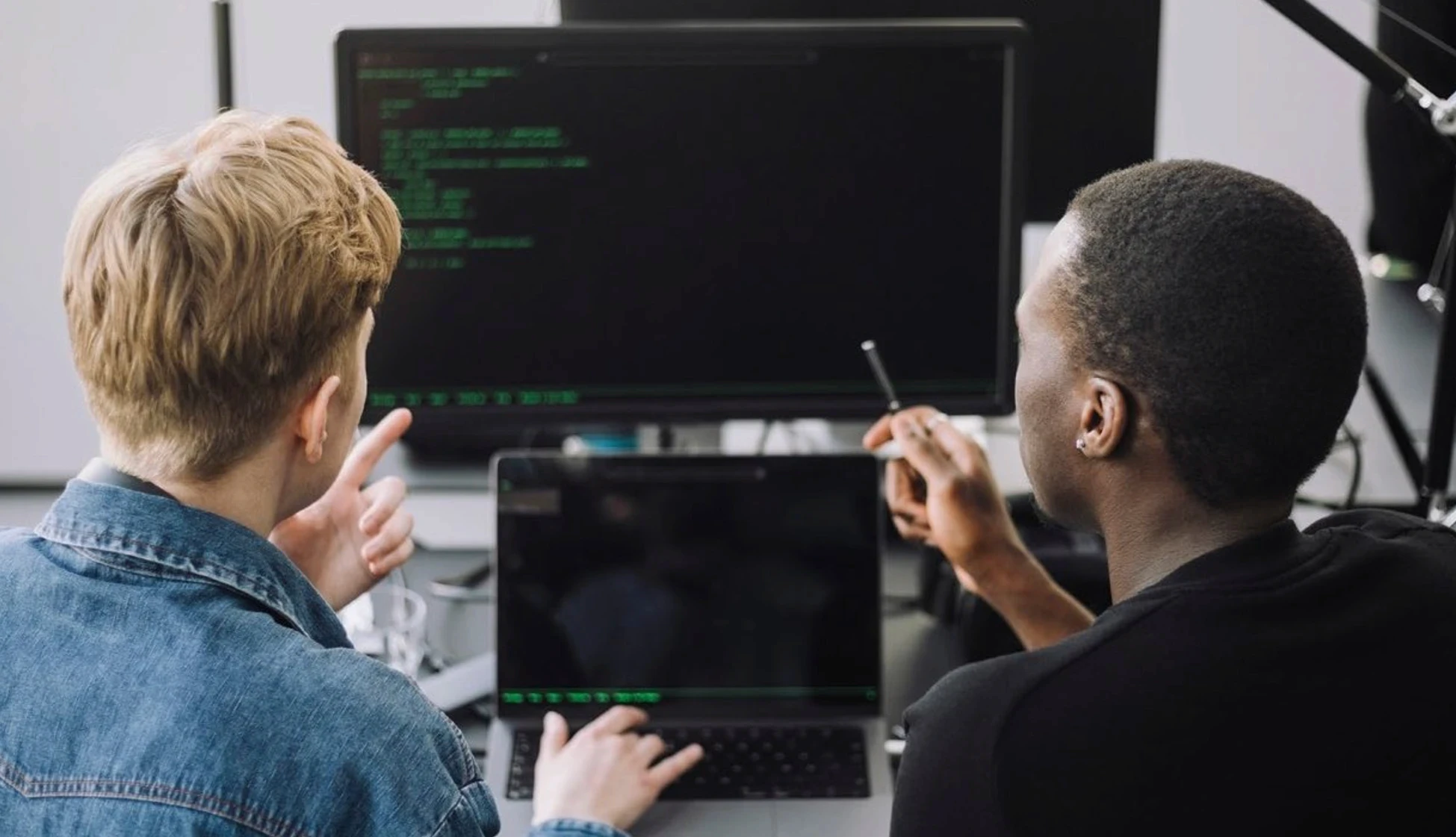 Two engineers reviewing code together at a monitor