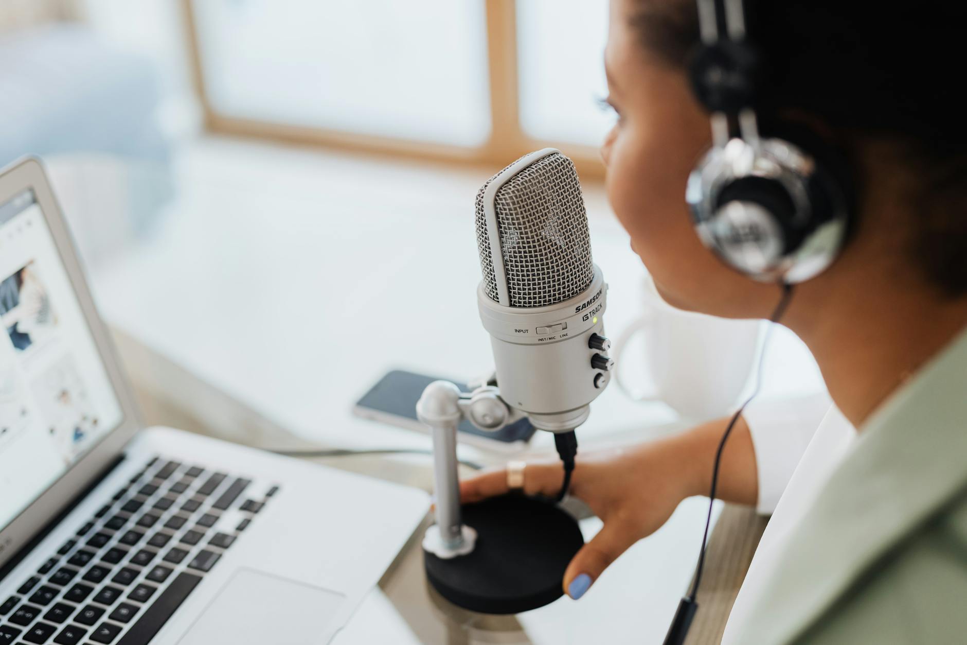 A professional woman with a warm smile recording a podcast in a home studio with a high-quality microphone.
