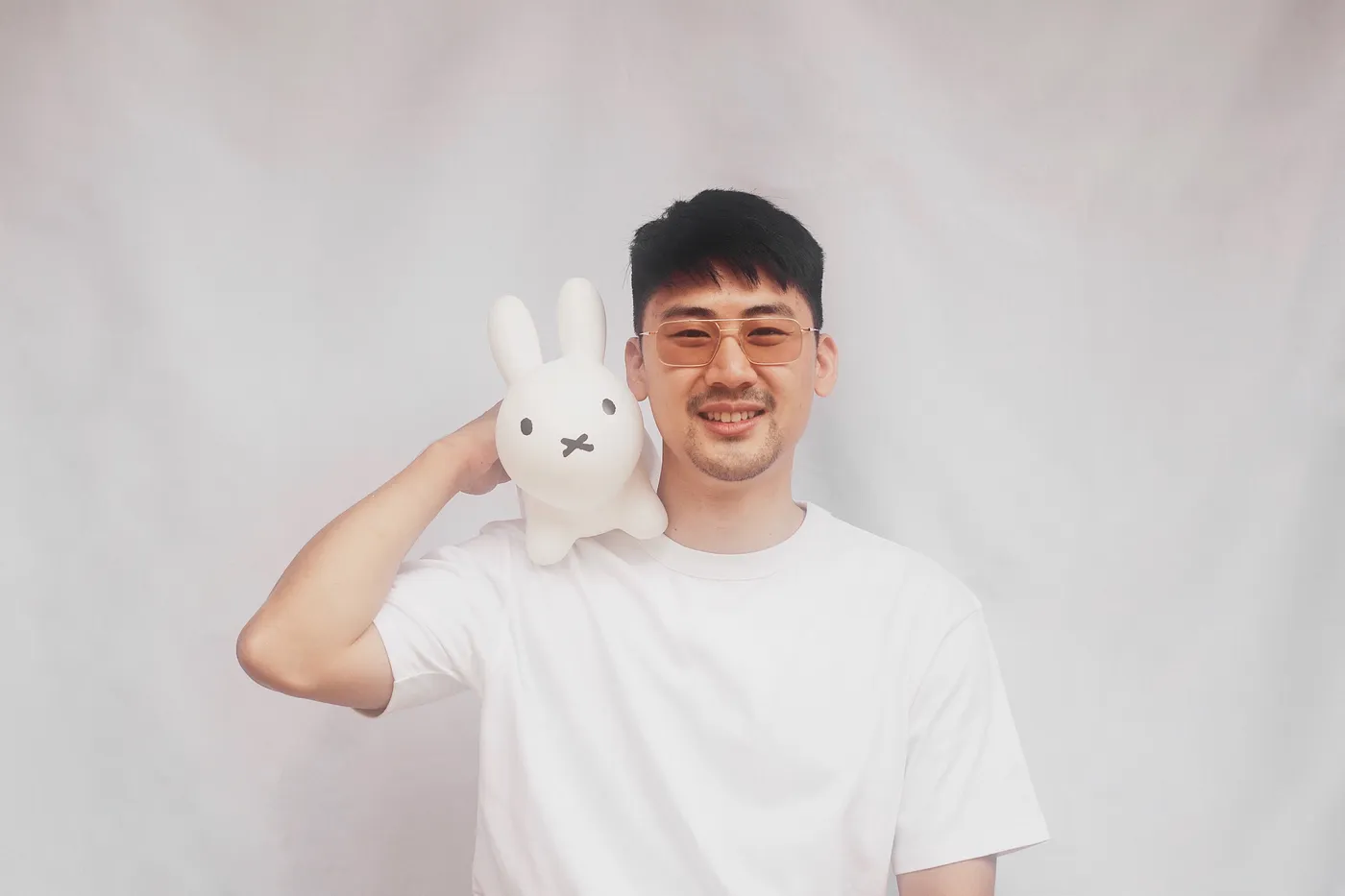 An image of Luke with a Miffy toy on his right shoulder, against a light grey backdrop.