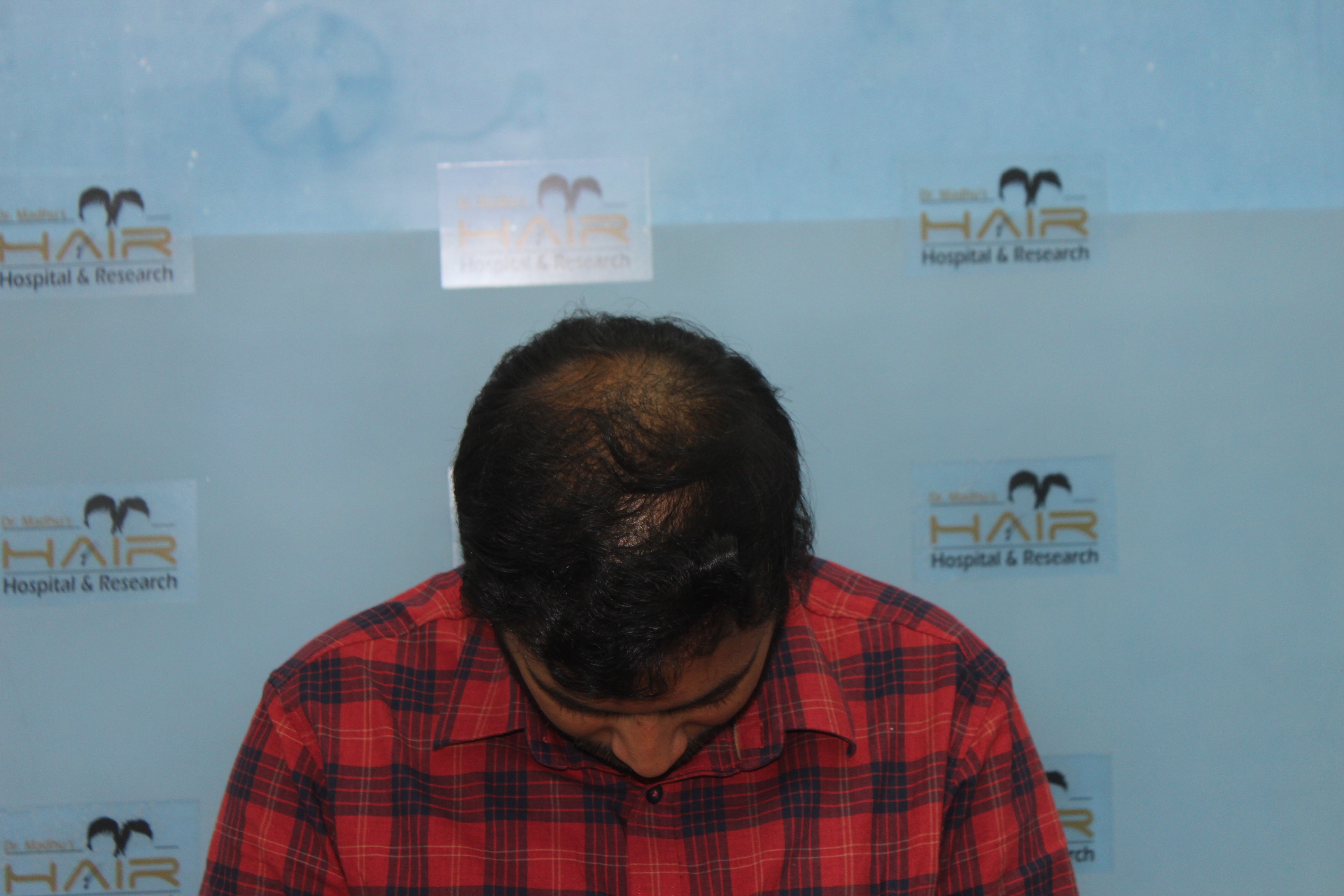 Smiling person in glasses outdoors with trees in background