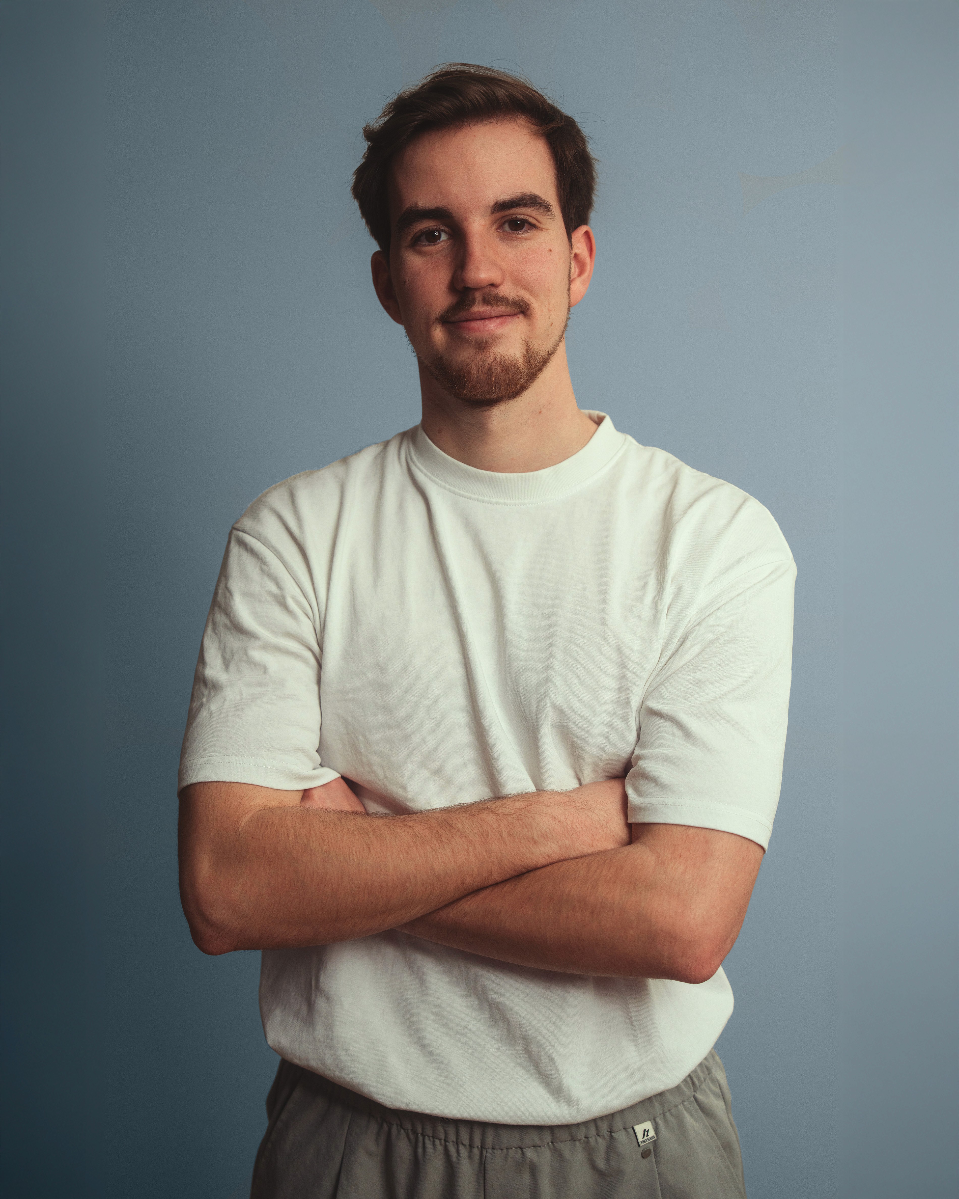 A man in a white shirt poses, conveying filmproduction and campaign creation.