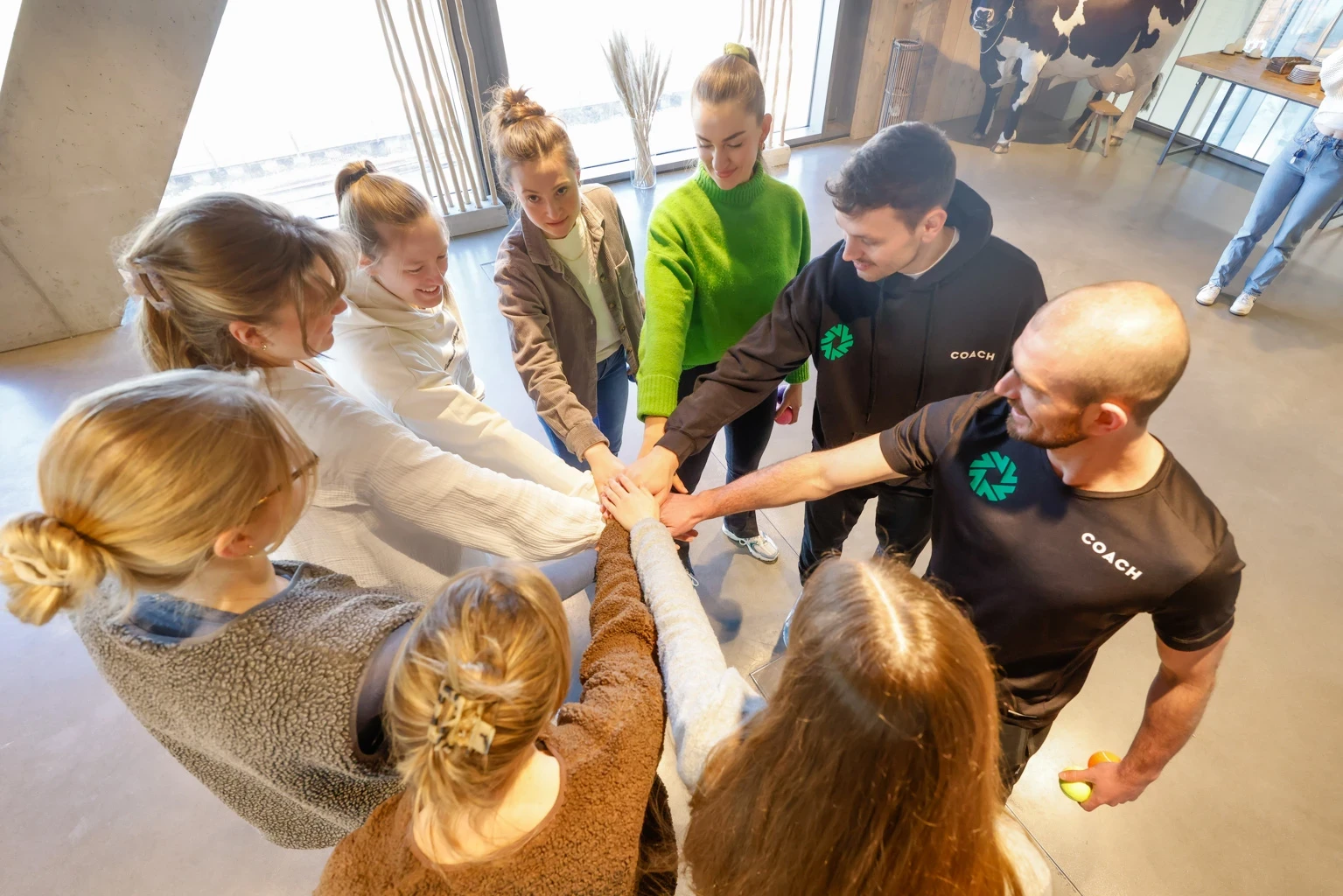 Junge Leute stehen im Kreis und halten die Hände übereinander