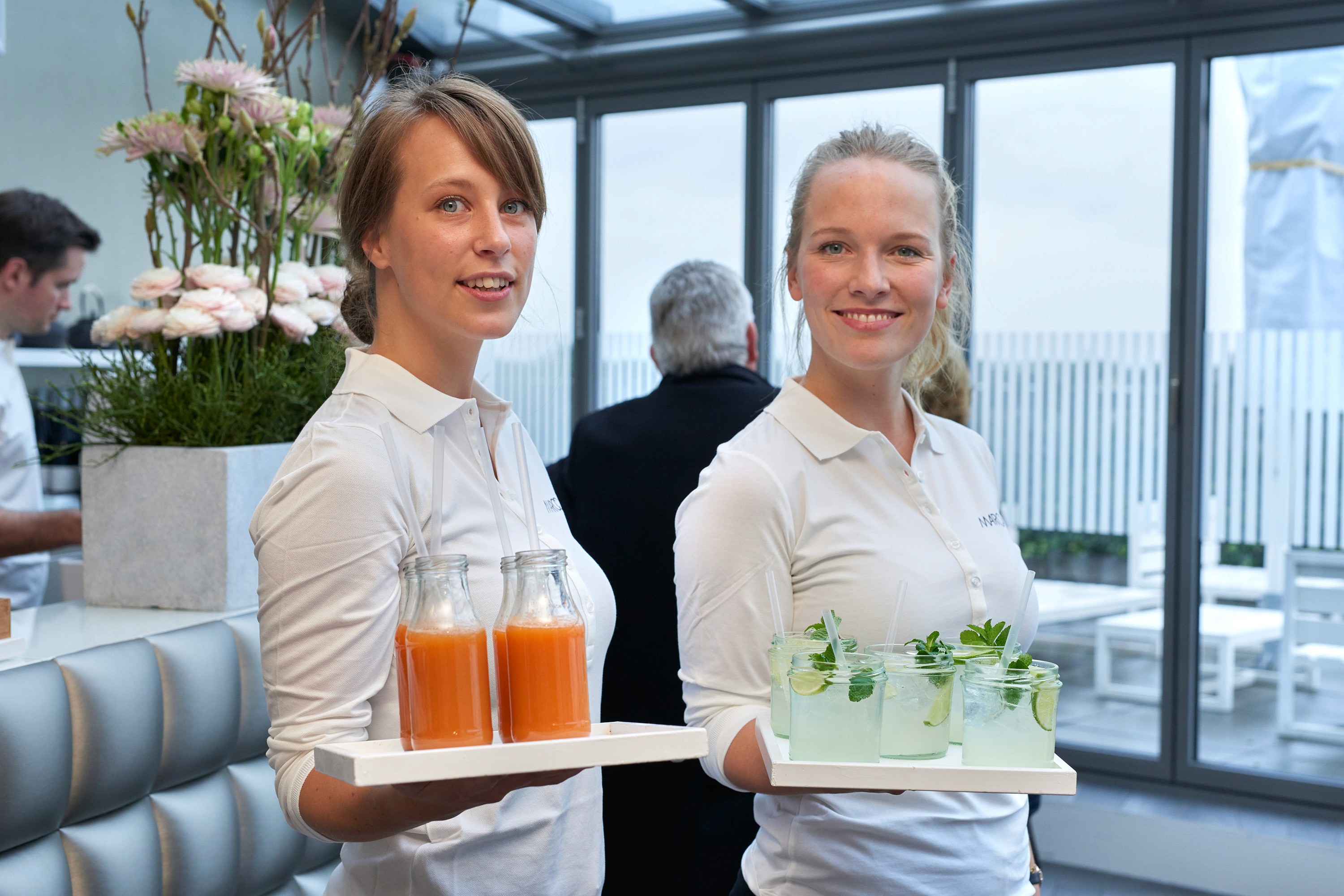 Zwei Servicekräfte mit frischen Säften im Hospitality-Bereich