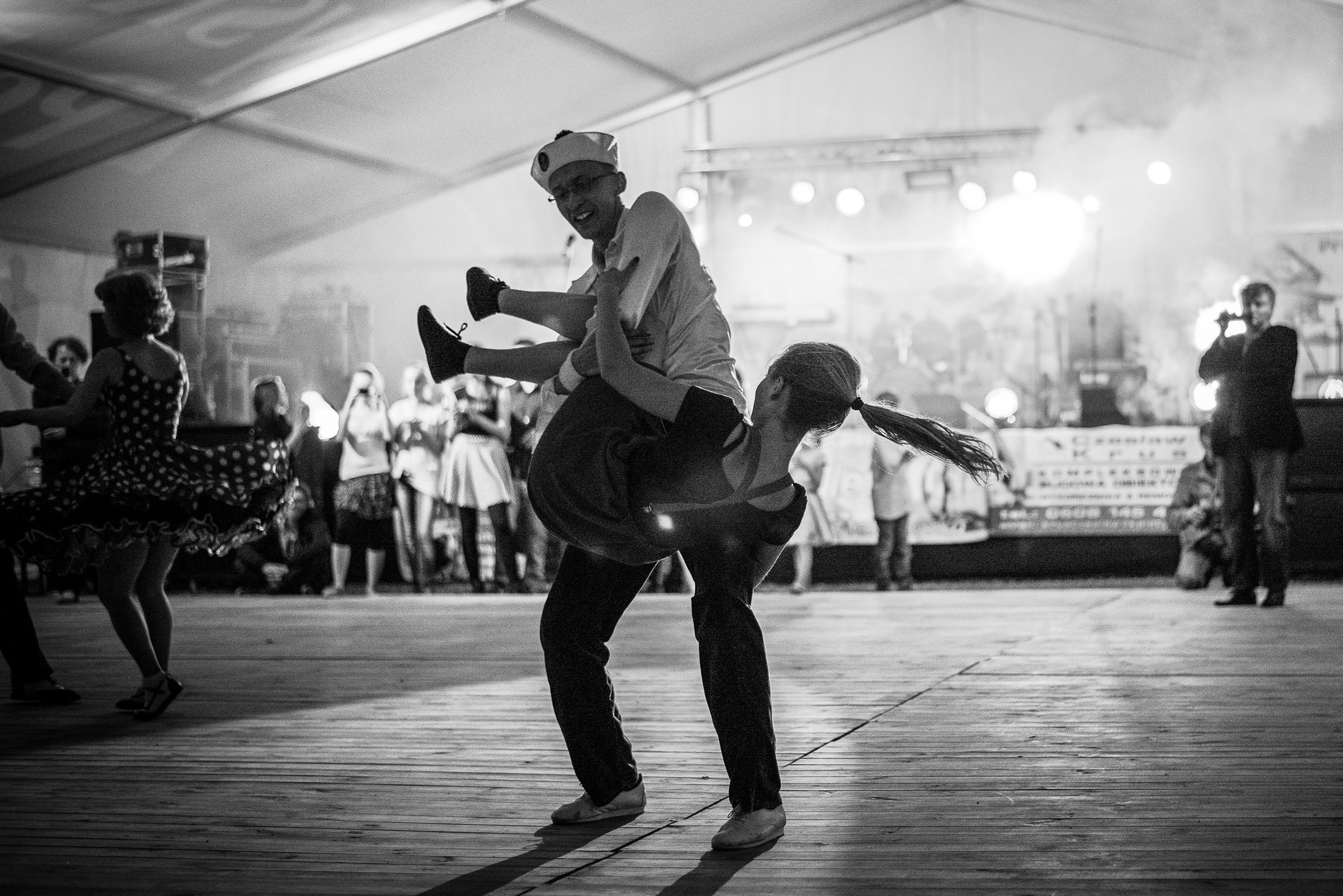 Czarno-biały kadr z festynu. Para tańczy Rock'n'rolla na turnieju.