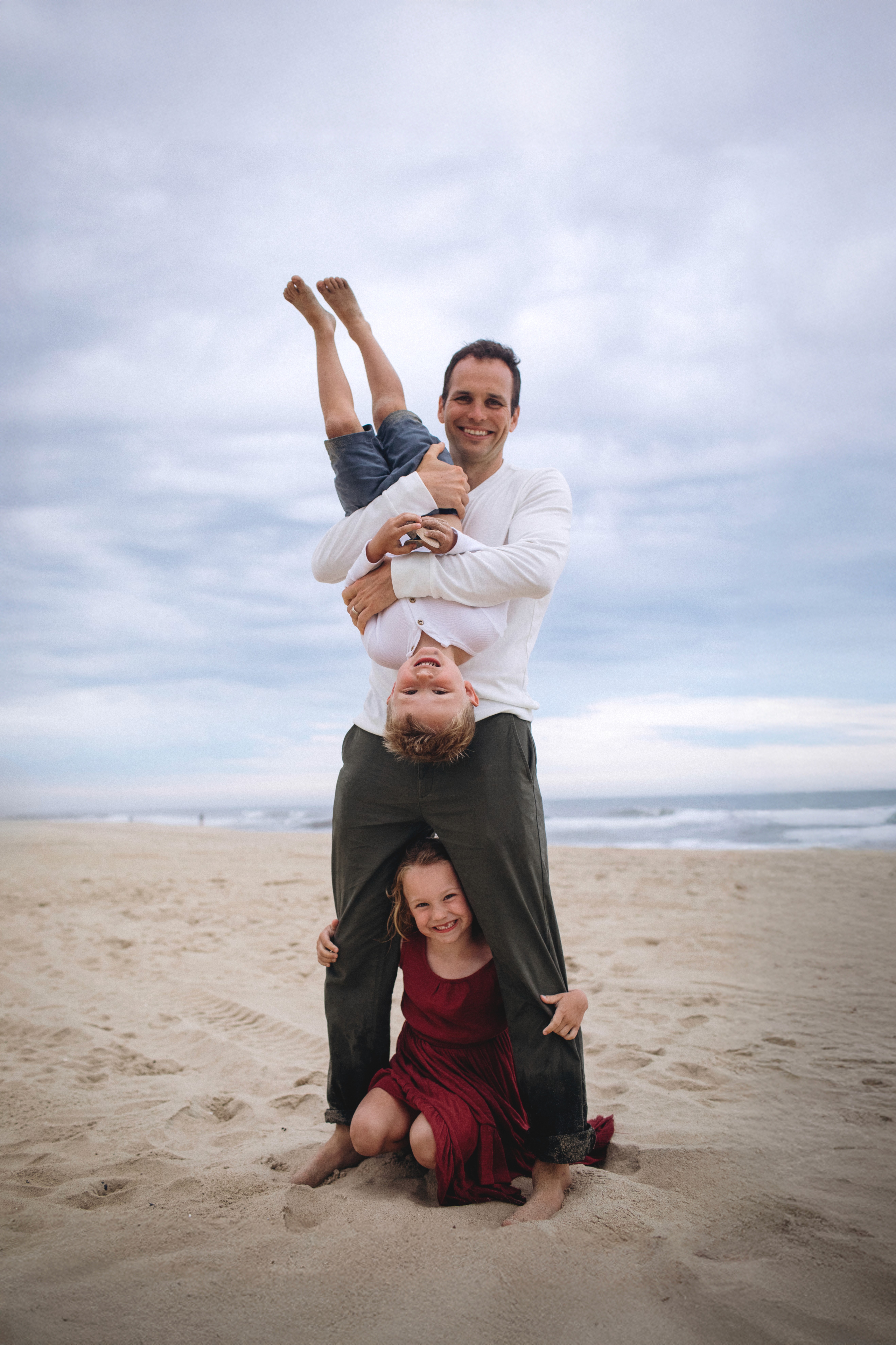 Father lifting his kids playfully during a joyful family photoshoot at the beach in San Diego.