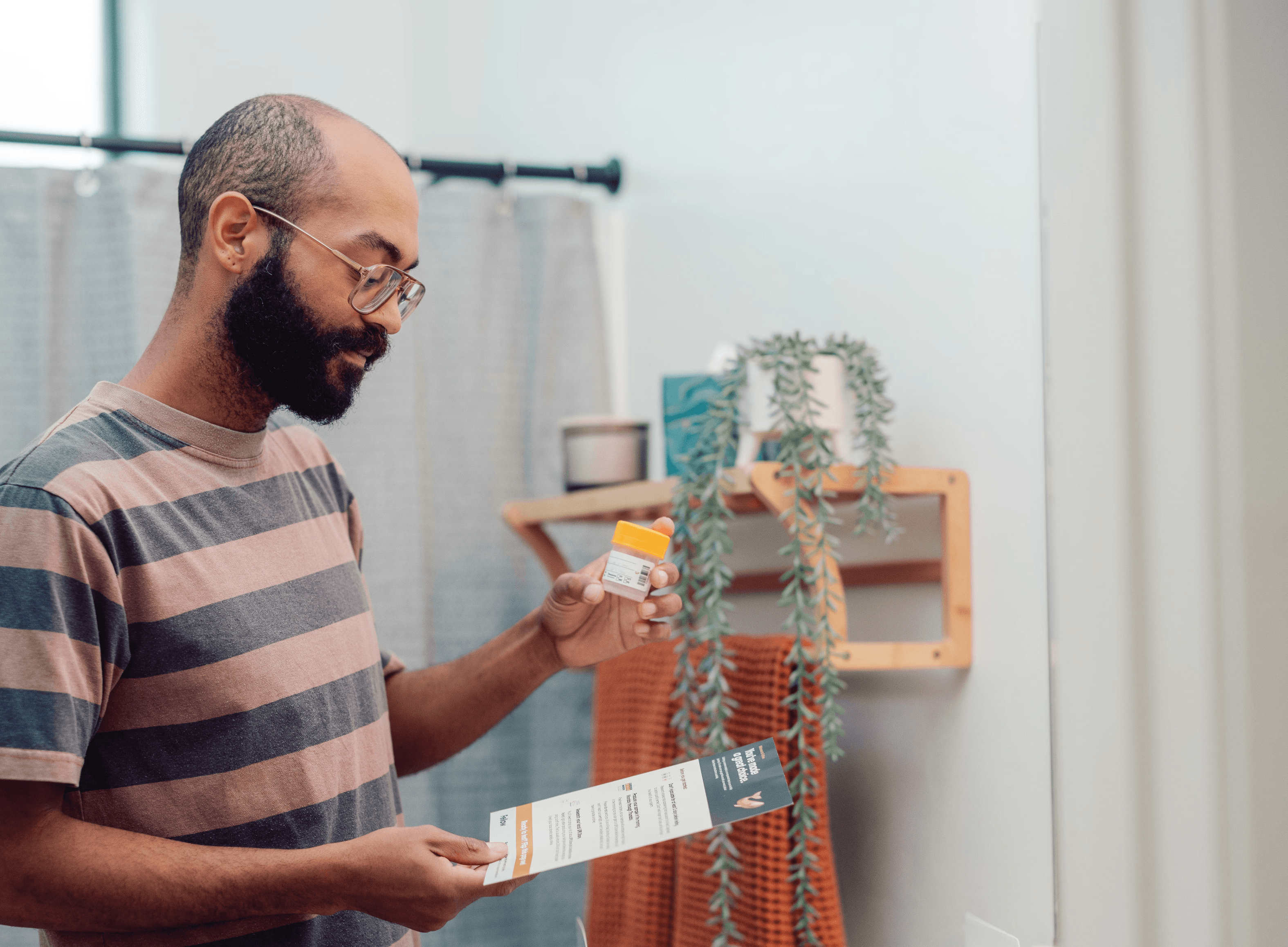 A young Black man looks at the Fellow testing kit in a bathroom