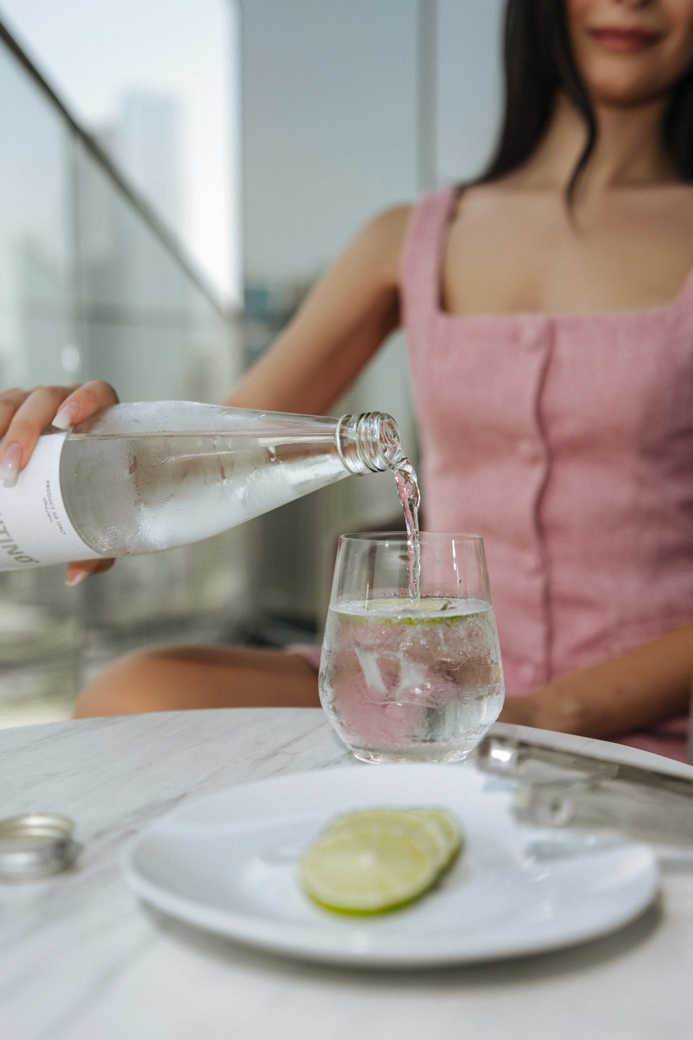 A lady pouring herself a glass of mineral water.