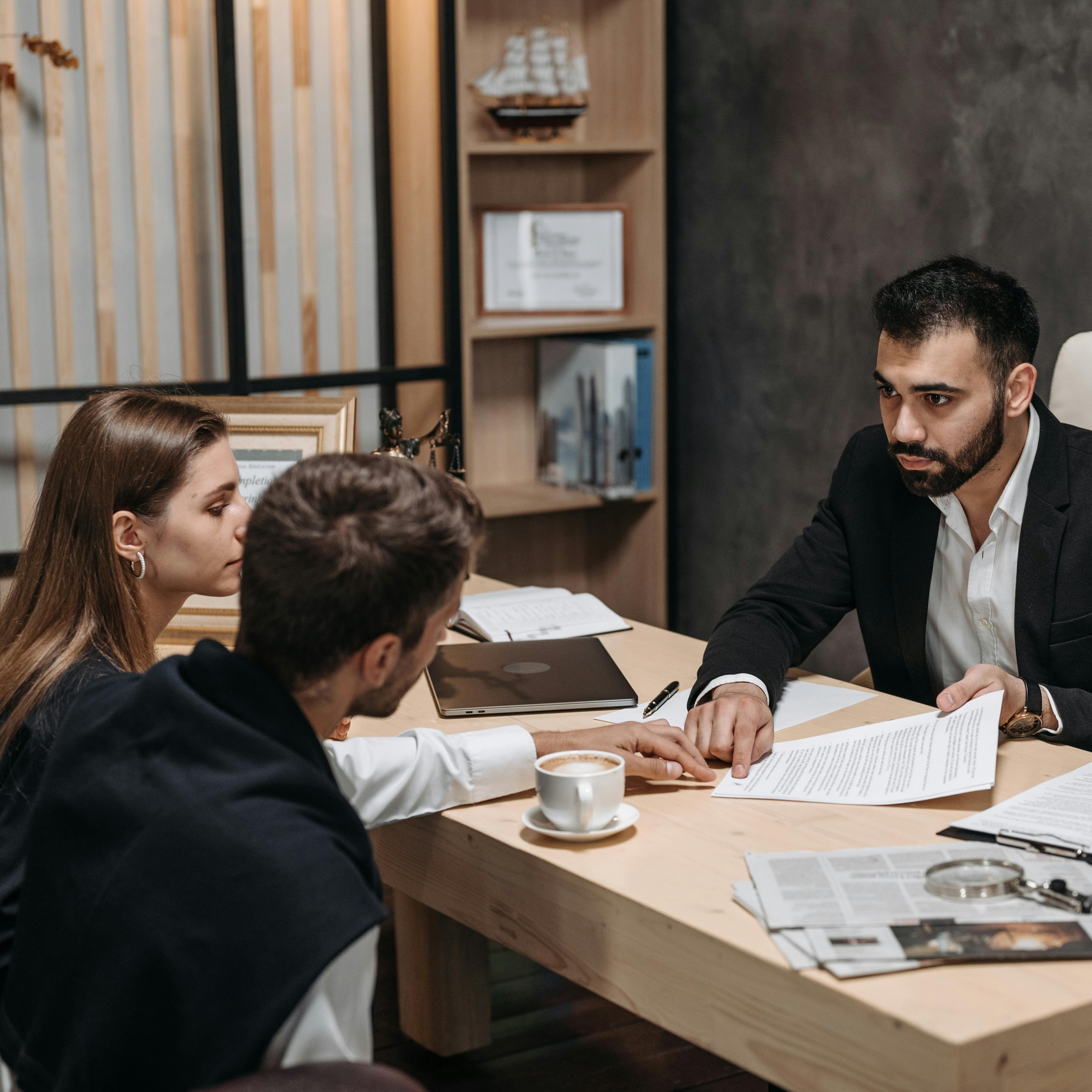 Business professional reviewing documents with two clients during a consultation meeting