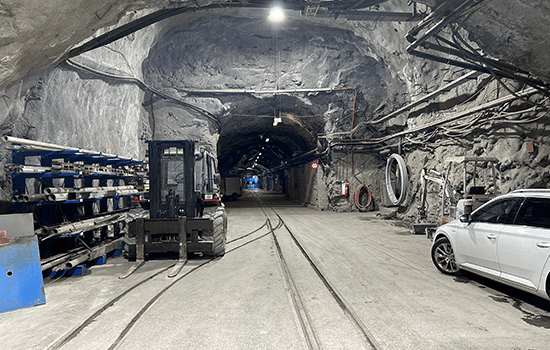 Four diverse professionals collaboratively working on a laptop, with one person pointing at the screen while others observe.