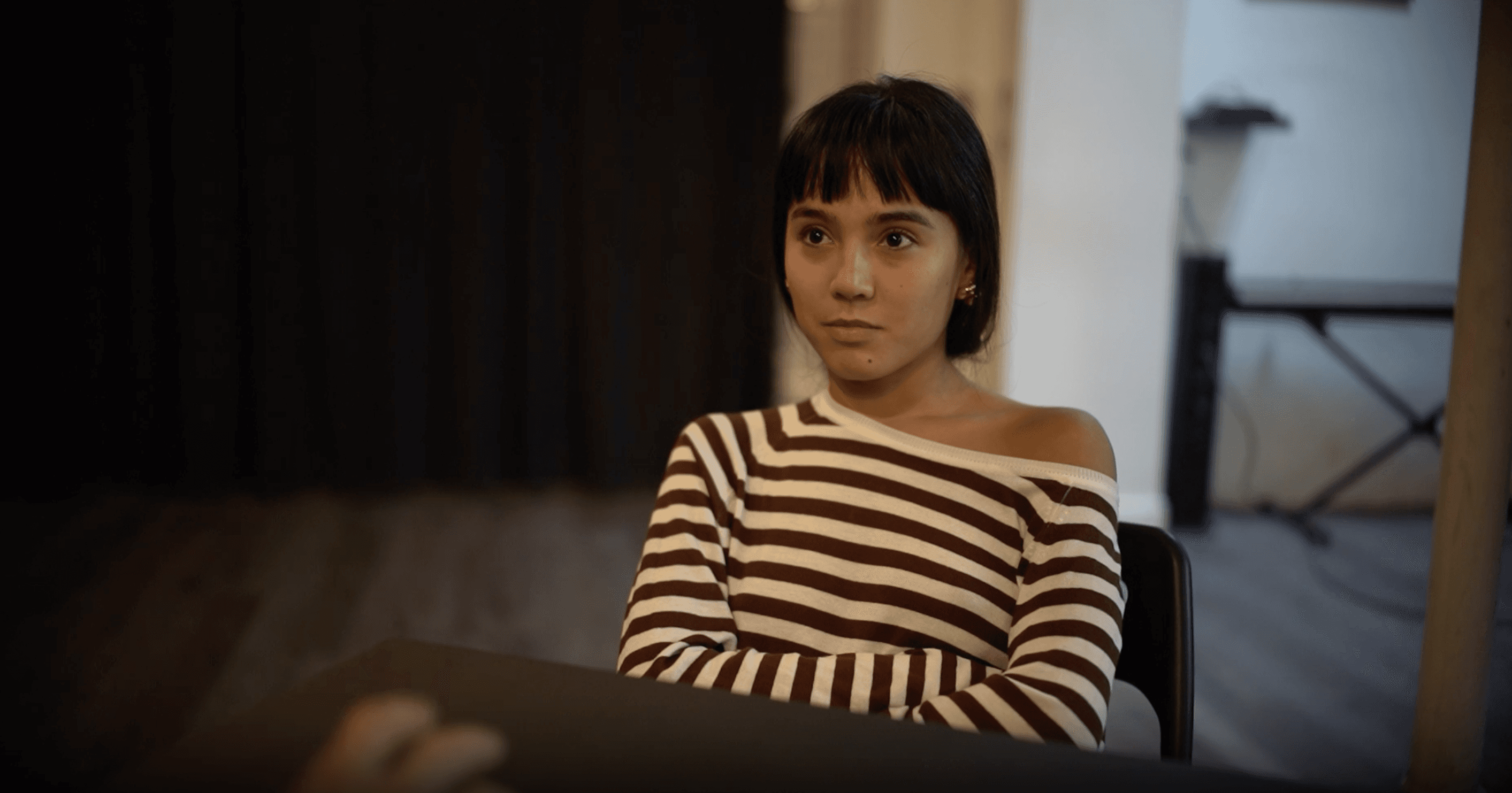 Woman in pink leather jacket crouching outdoors at night