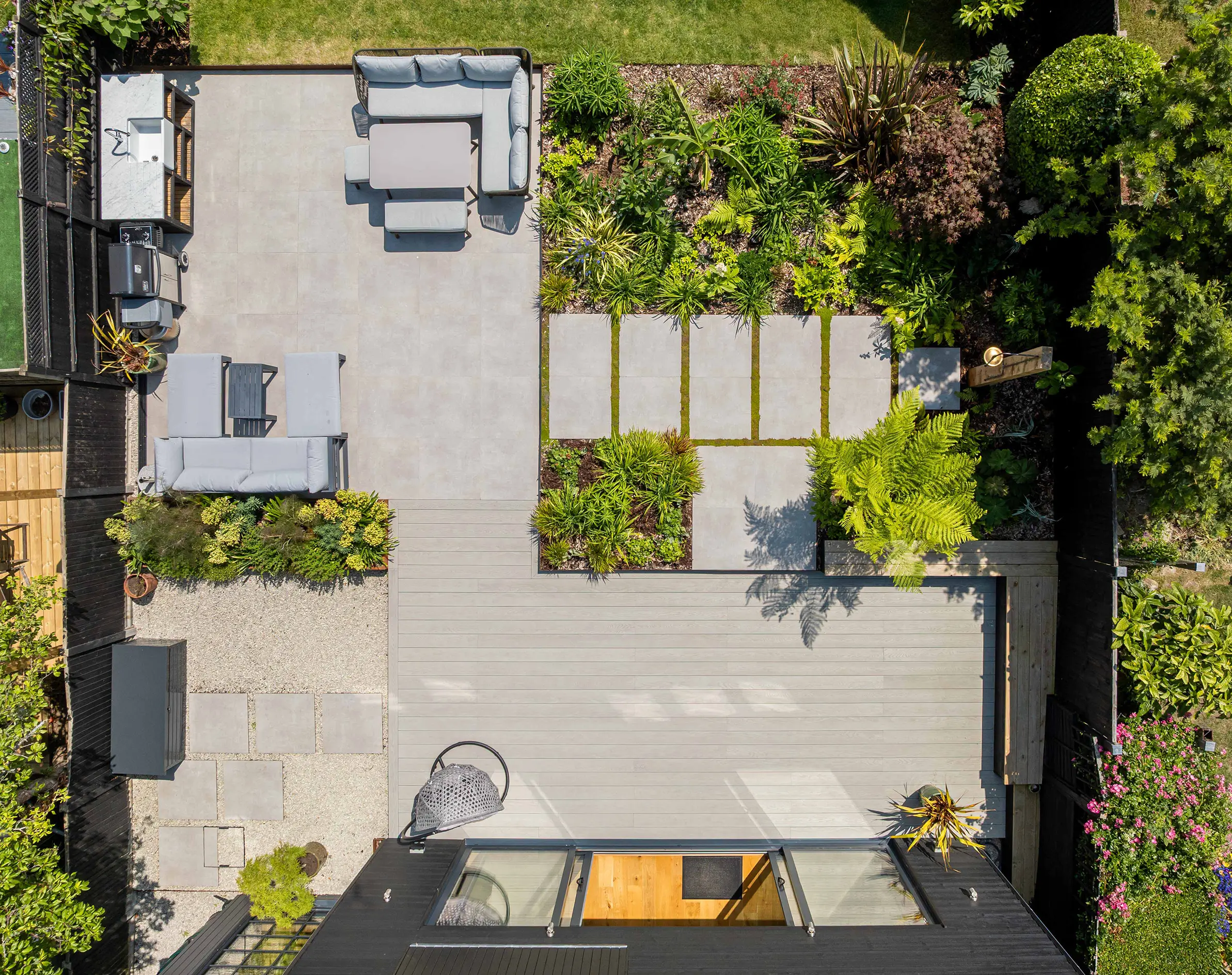 An aerial view of a landscaped patio featuring seating areas and greenery, surrounded by stone pathways.