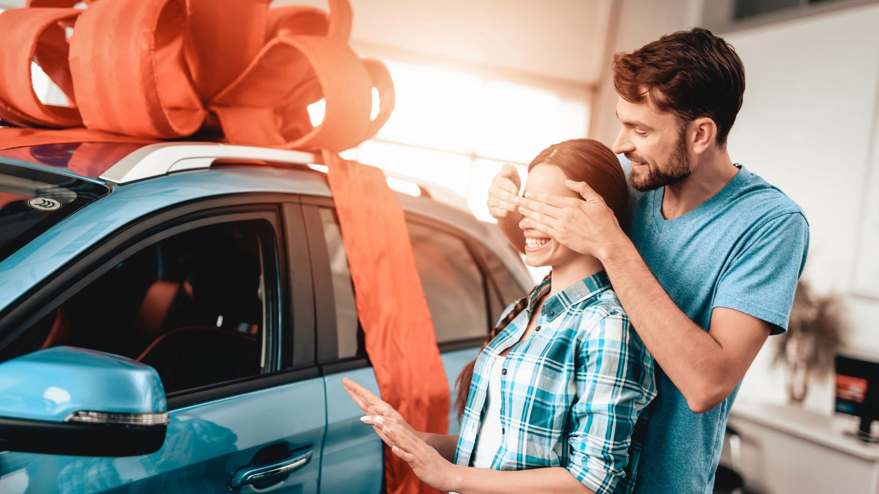 Rodzice wręczają kluczyki do samochodu nastolatkowi przy aucie.