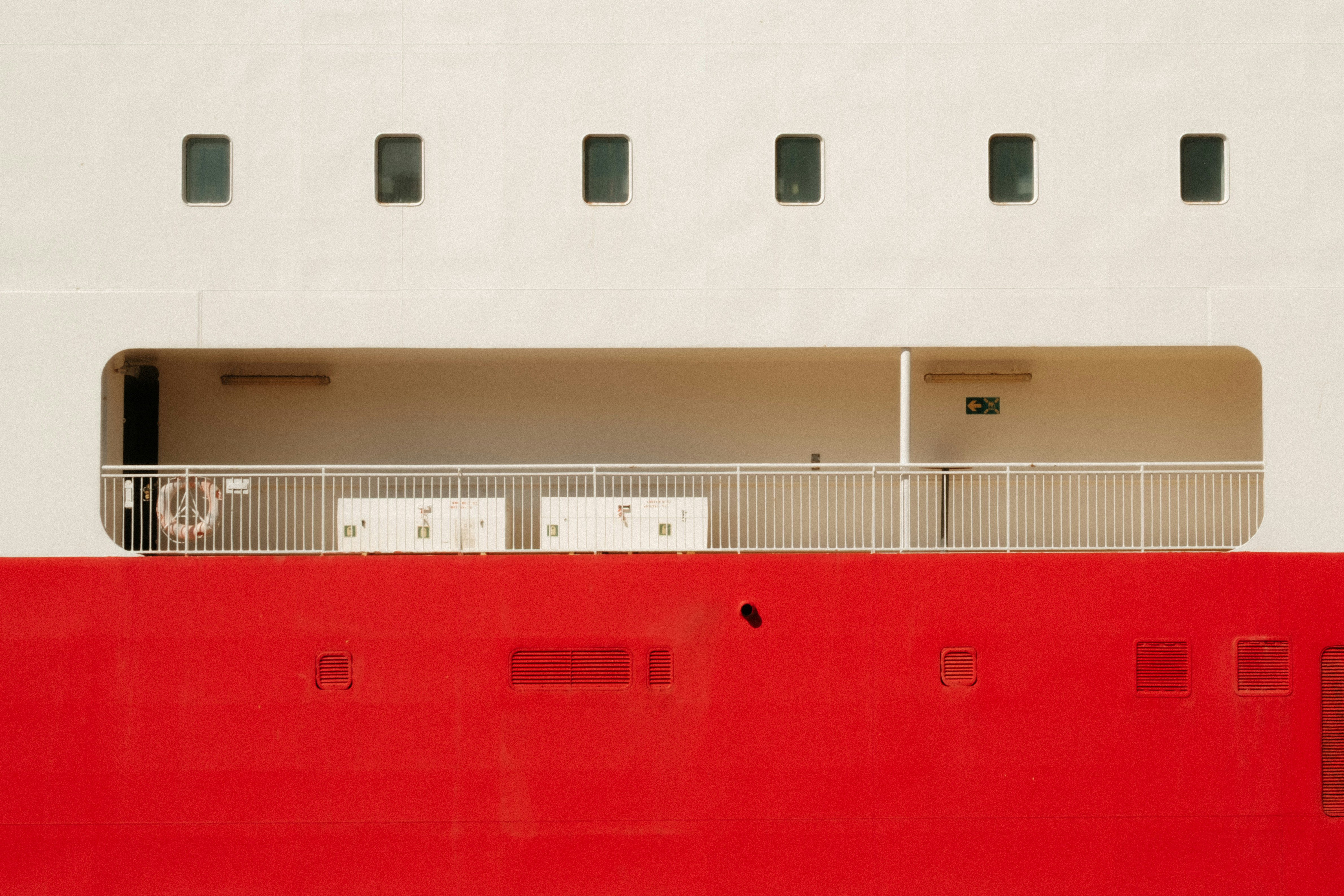 A white ship deck with a red hull and a metal railing
