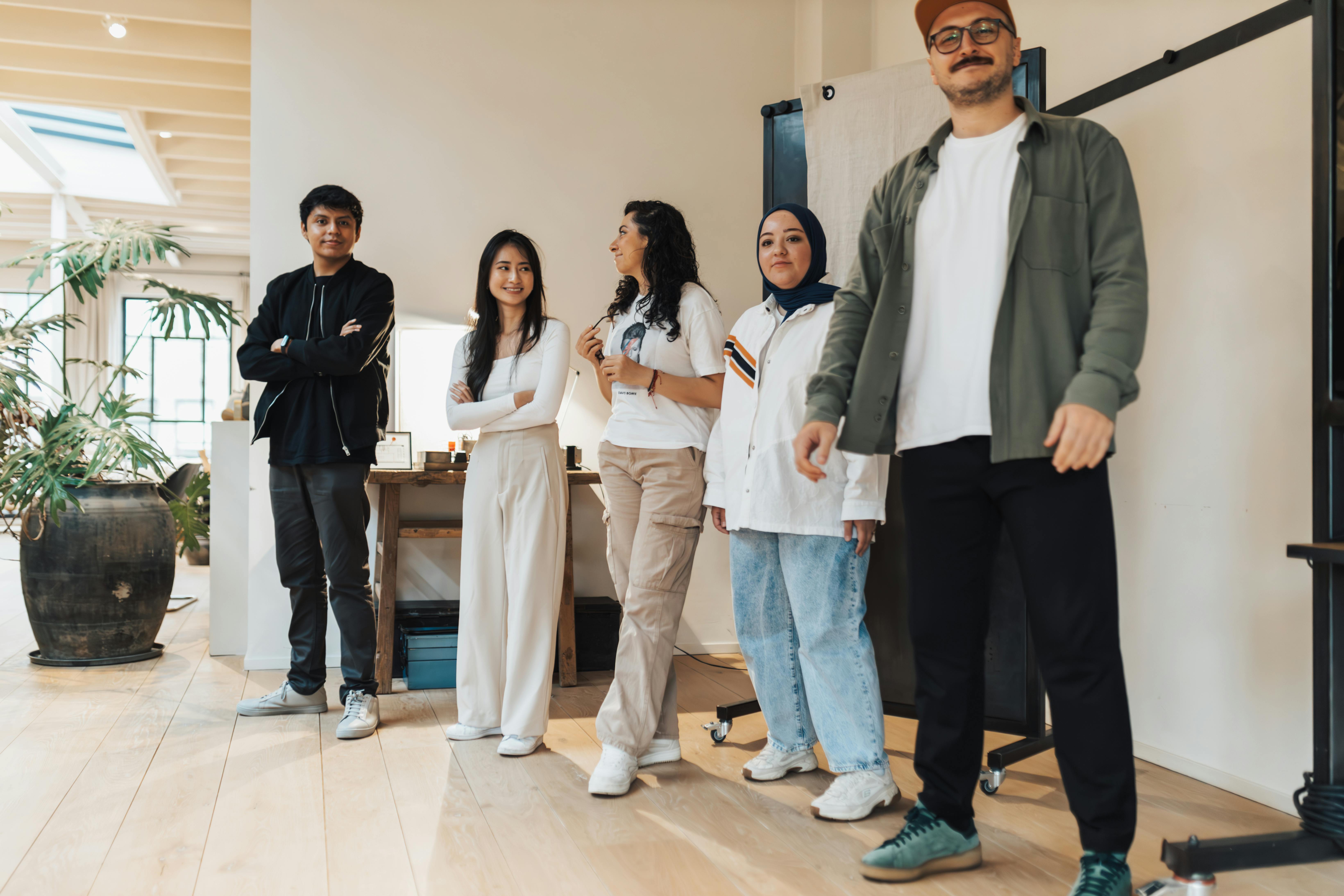 Diverse group of young professionals smiling in a modern office environment, highlighting teamwork and inclusivity.