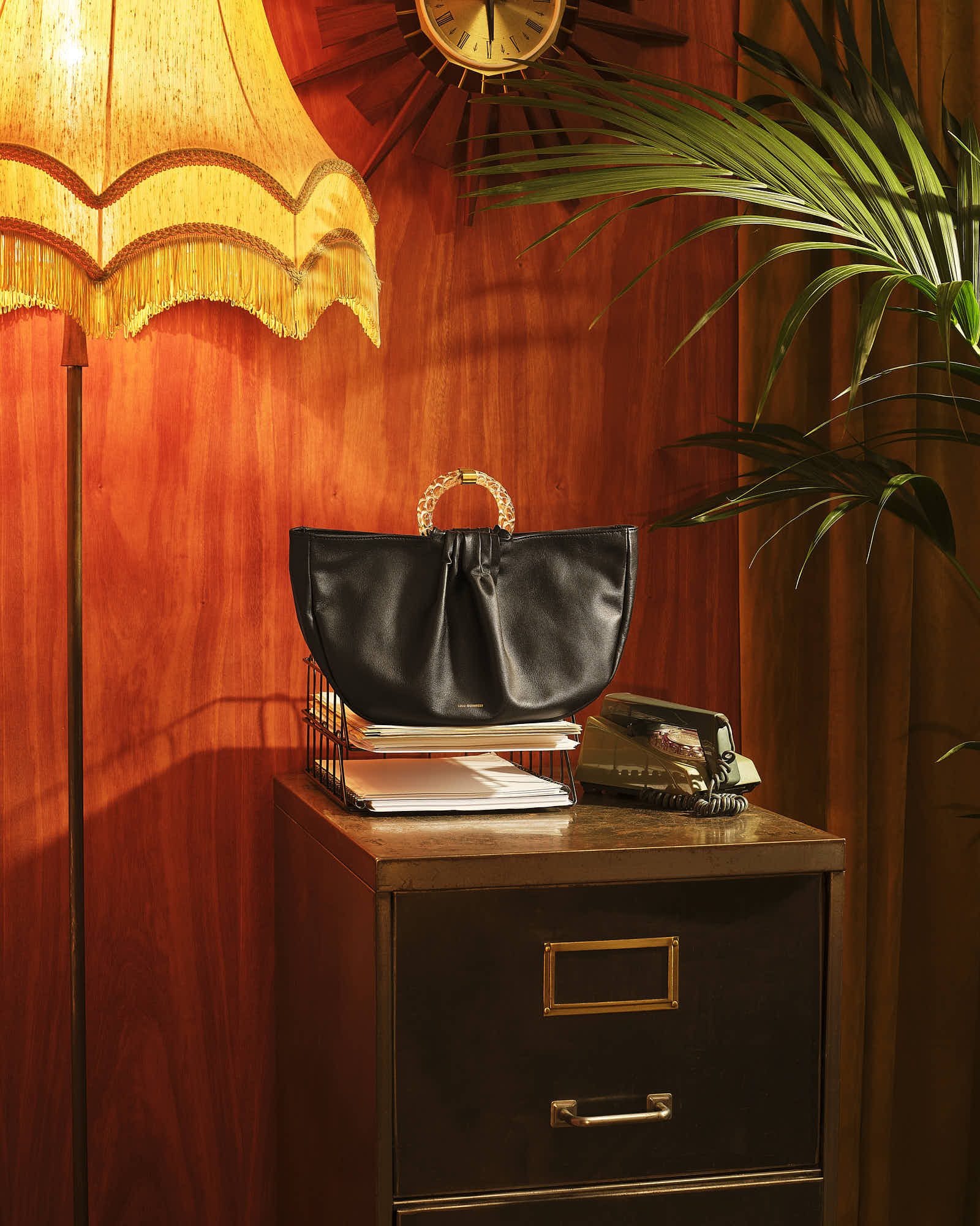 Vintage office decor with black handbag, retro phone, and lamp.