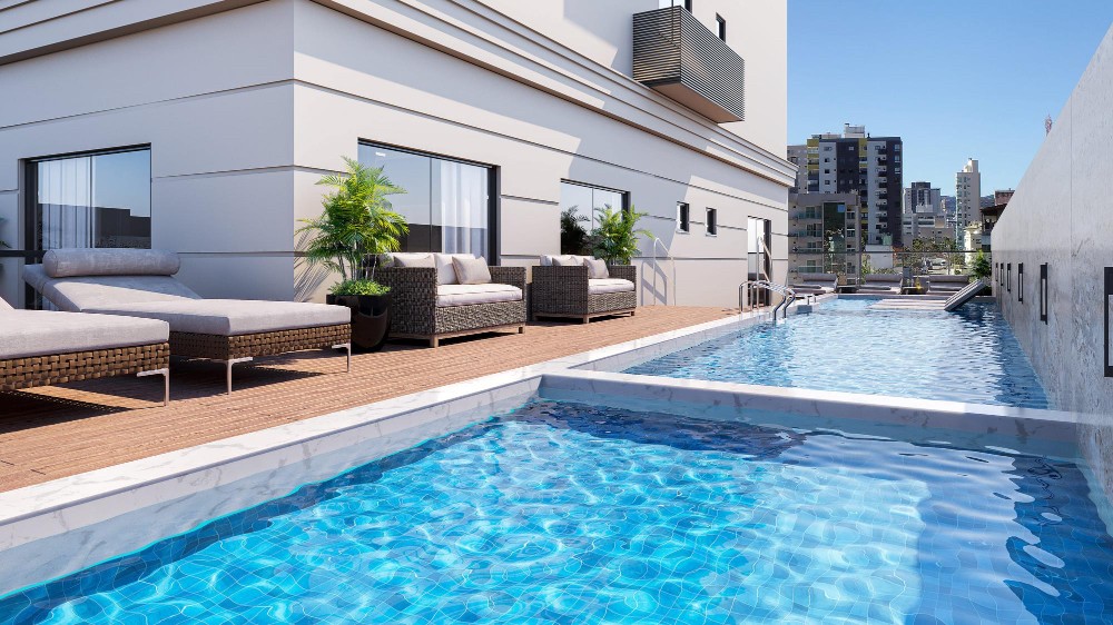 High-rise rooftop pool overlooking the city skyline, surrounded by glass fencing and timber decking.