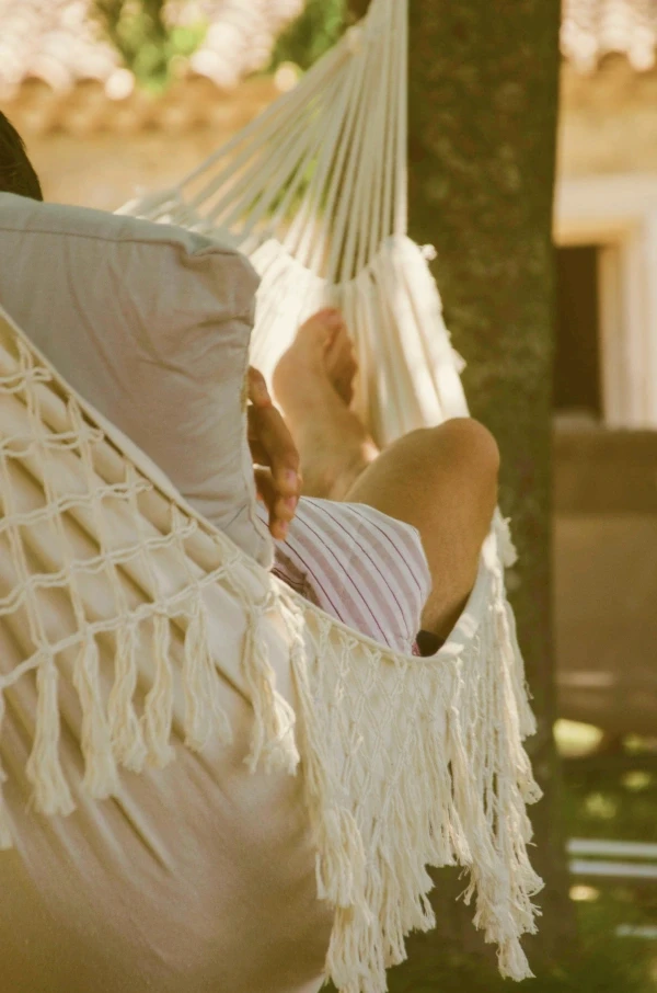Someone relaxing in a hammock in dappled shade.