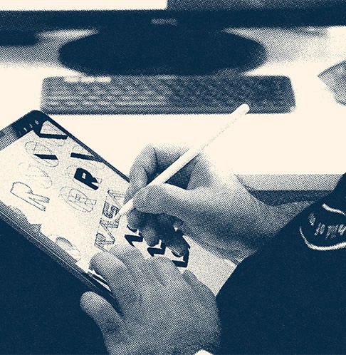 Services graphic showing a close up image of a person drawing logos on a tablet.