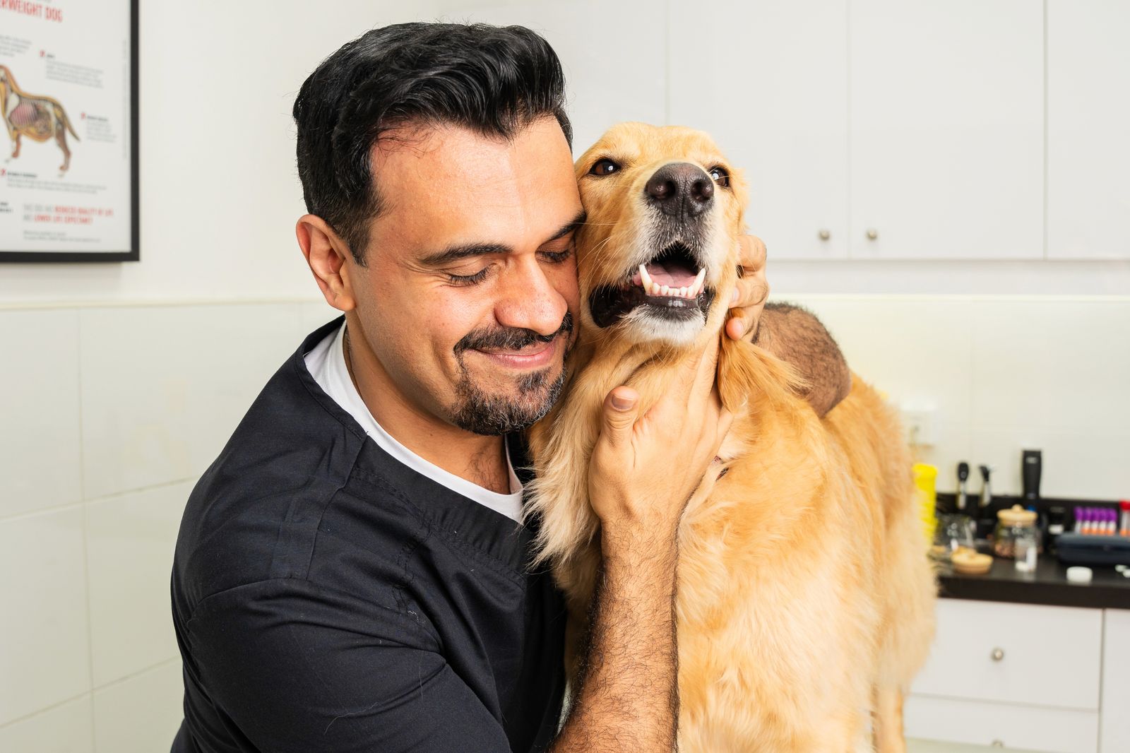 Veterinarian smiling while holding a happy golden retriever during a routine checkup at a pet clinic.