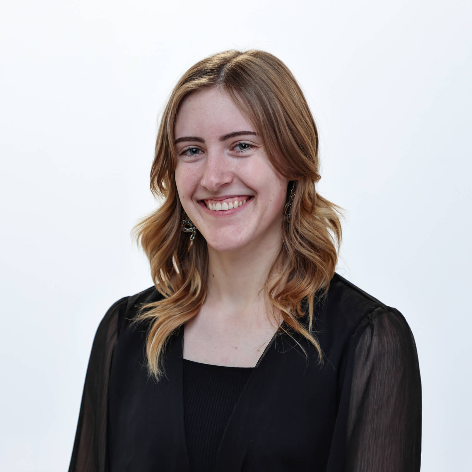A headshot of Sydney smiling in front of a white background