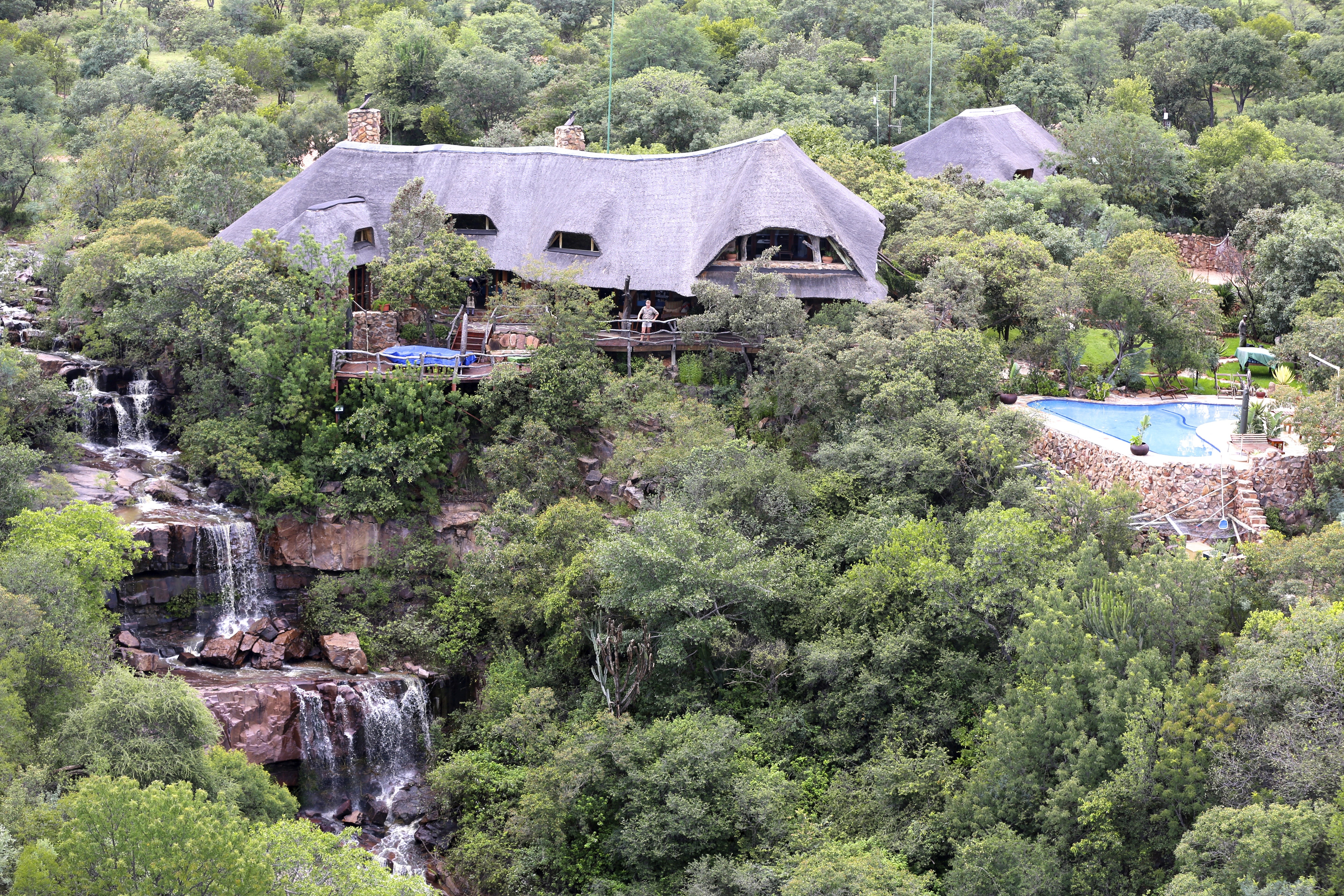 En grupp elefanter passerar framför kameran i Mashatu Game Reserve, Botswana. I bakgrunden betraktar ryttare till häst på ridsafari elefanterna när de passerar genom det afrikanska landskapet. En dag på ridsemester, Tuli Safari, Afrika. 