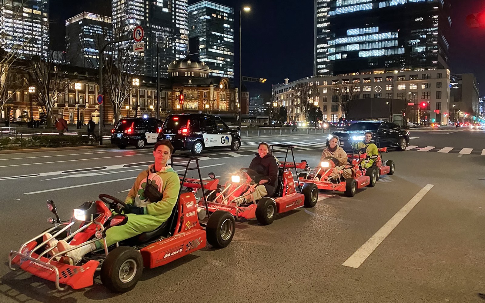 在東京秋葉原,夜晚的城市燈光下,人們正在駕駛卡丁車。