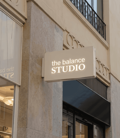 Close-up of a freckled woman behind a translucent film strip—soft, dewy skin, minimal beauty editorial on white.