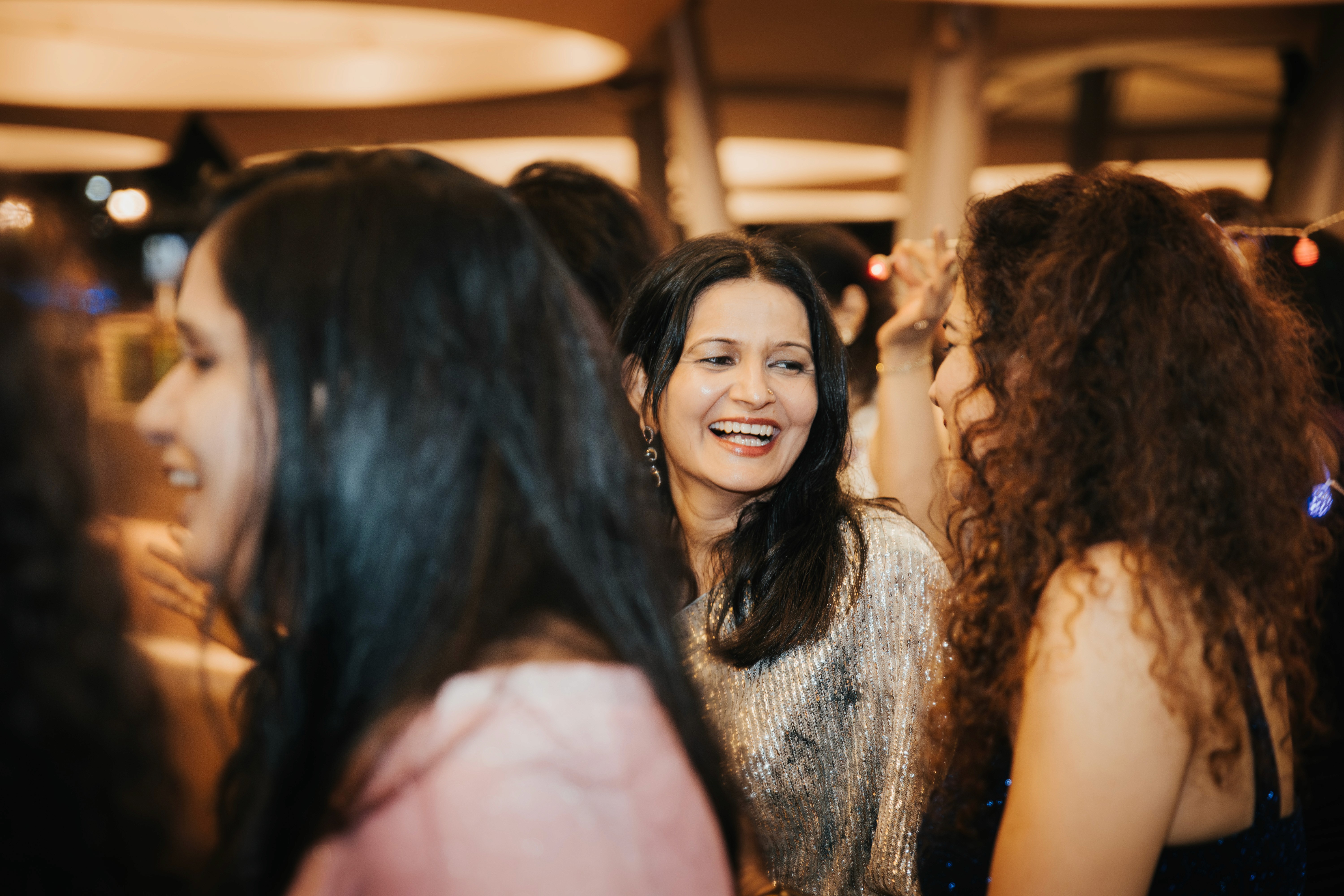 Candid shot of the bride laughing during a speech at an Indian anniversary dinner.