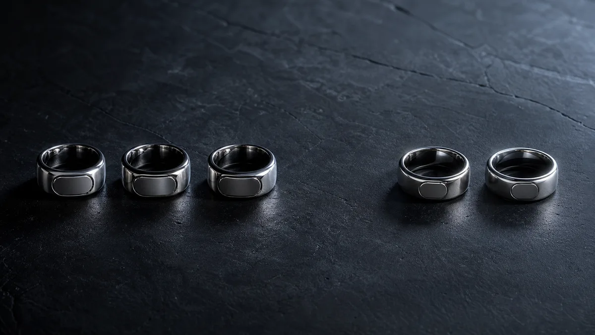 Five smart tasbih rings grouped as three and two on dark stone
