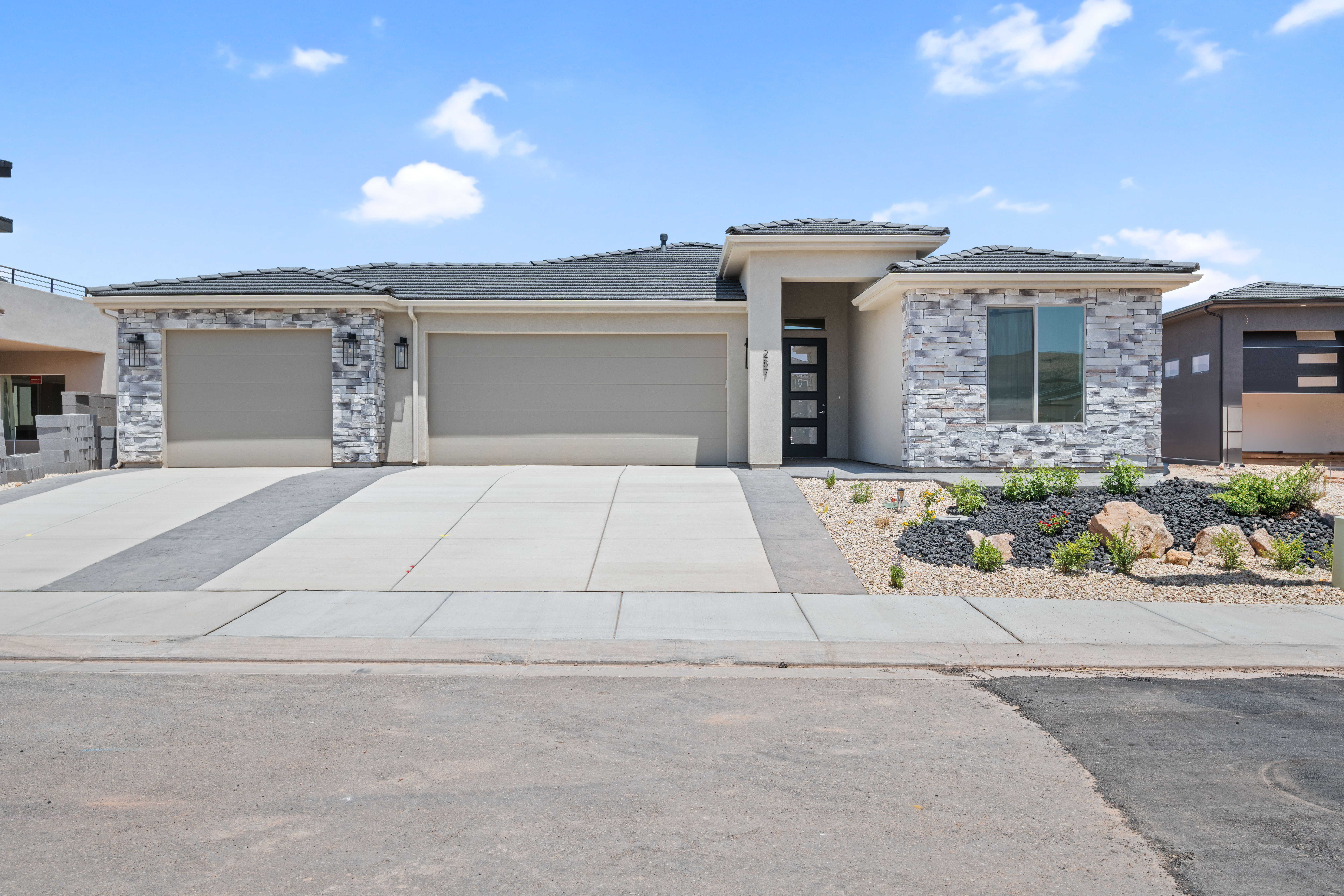 Front view of The Nest at Falcon Ridge custom home in Hurricane, Utah, highlighting windows, rooflines, and surrounding greenery.